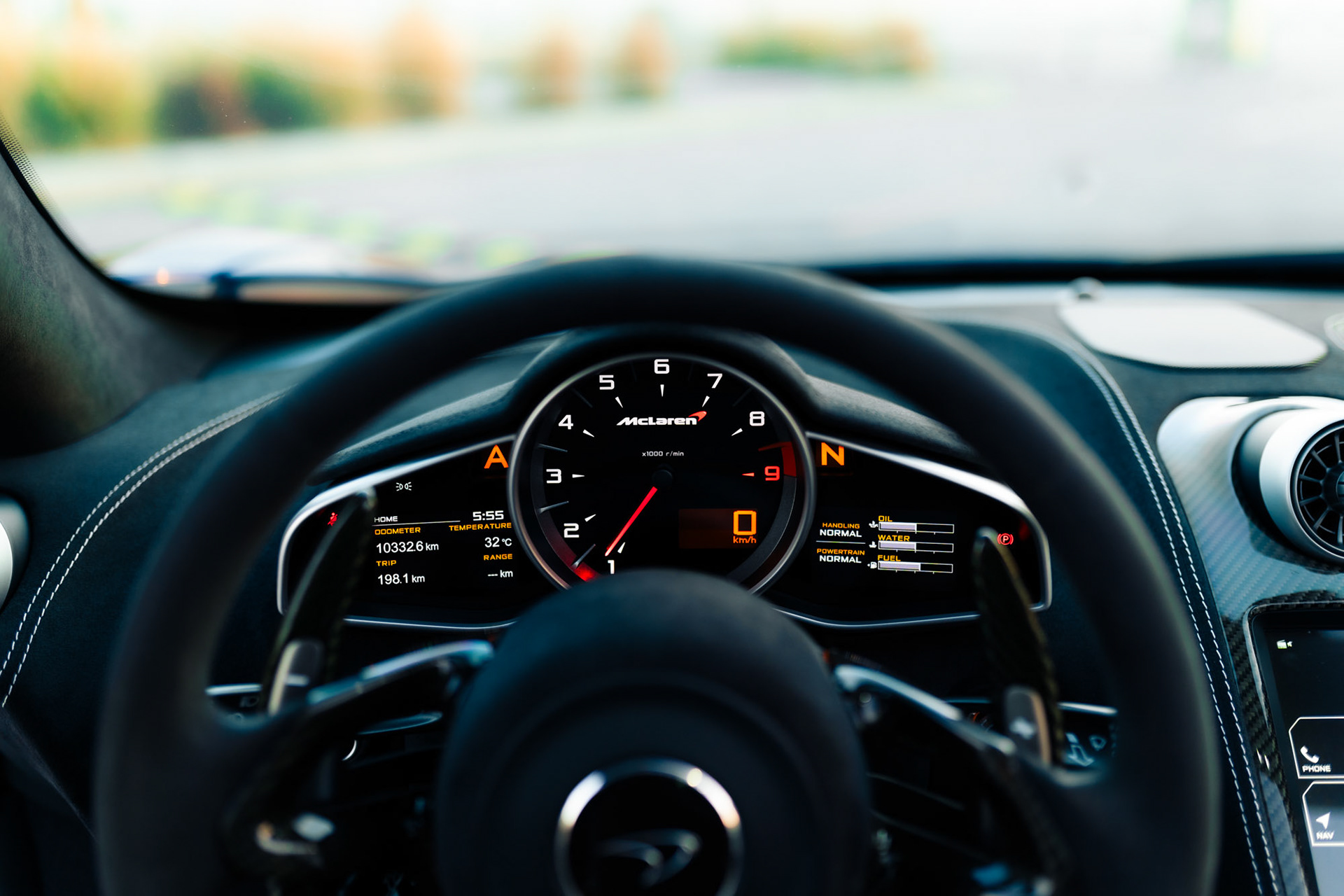 Driver’s perspective inside the McLaren 650S Spider, showing the steering wheel, central tachometer, and carbon-fiber dashboard details