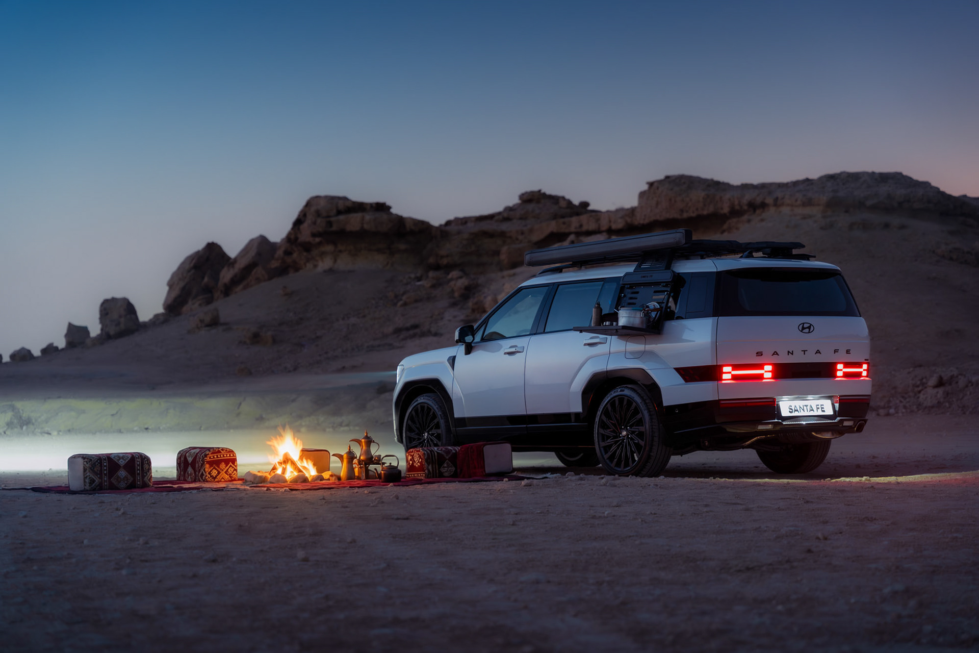 HYUNDAI SANTA FE rear three-quarter view with taillights lit at blue hour beside a desert camp, Bahrain — Shift Mootark