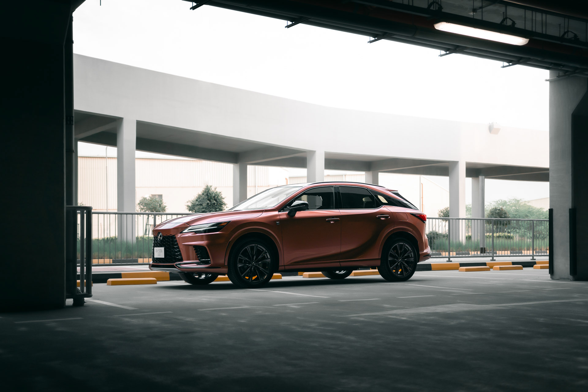  Three-quarter front view of the Lexus RX500h F SPORT in copper, captured under soft daylight with clean reflections and neutral tones.