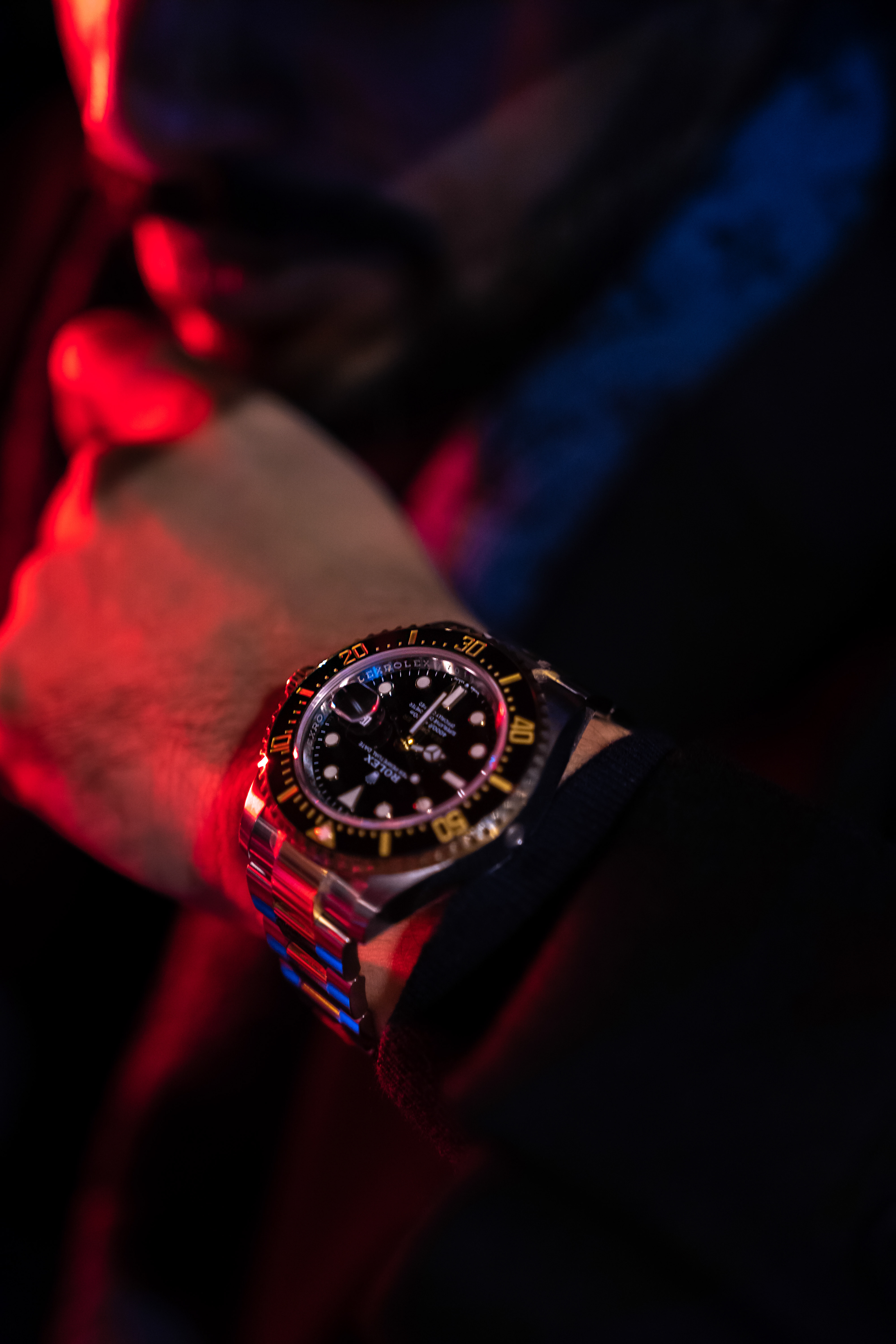 Lifestyle details beside a Lamborghini Urus—LV scarf, gold Rolex, and Lamborghini seat crest under red interior light