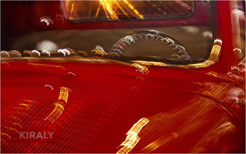 Slow shutter speed photo of a bright red, retro truck photographed at night and showing many reflections of light