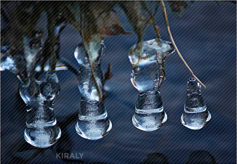 Photo of four line-up, dangling icicles hovering over a body of water and the formations look like figurines
