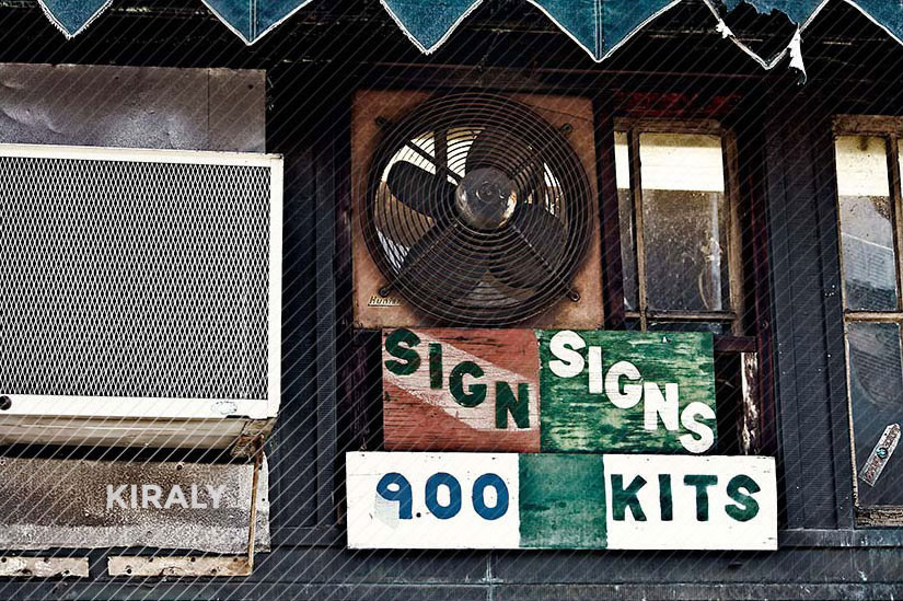 Photo of building with poorly hand painted signs selling sign making kits