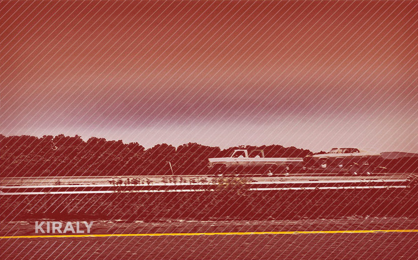 Photo of passing truck hauling an older car along highway