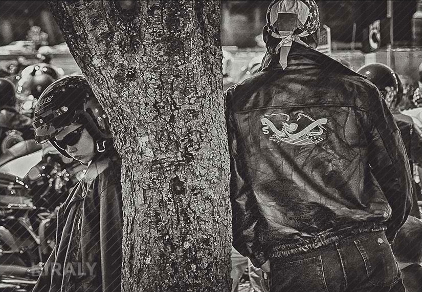 Unhappy boy leaning against tree opposite of father at Rolling Thunder