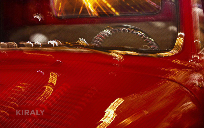 Slow shutter speed photo of a bright red, retro truck photographed at night and showing many reflections of light