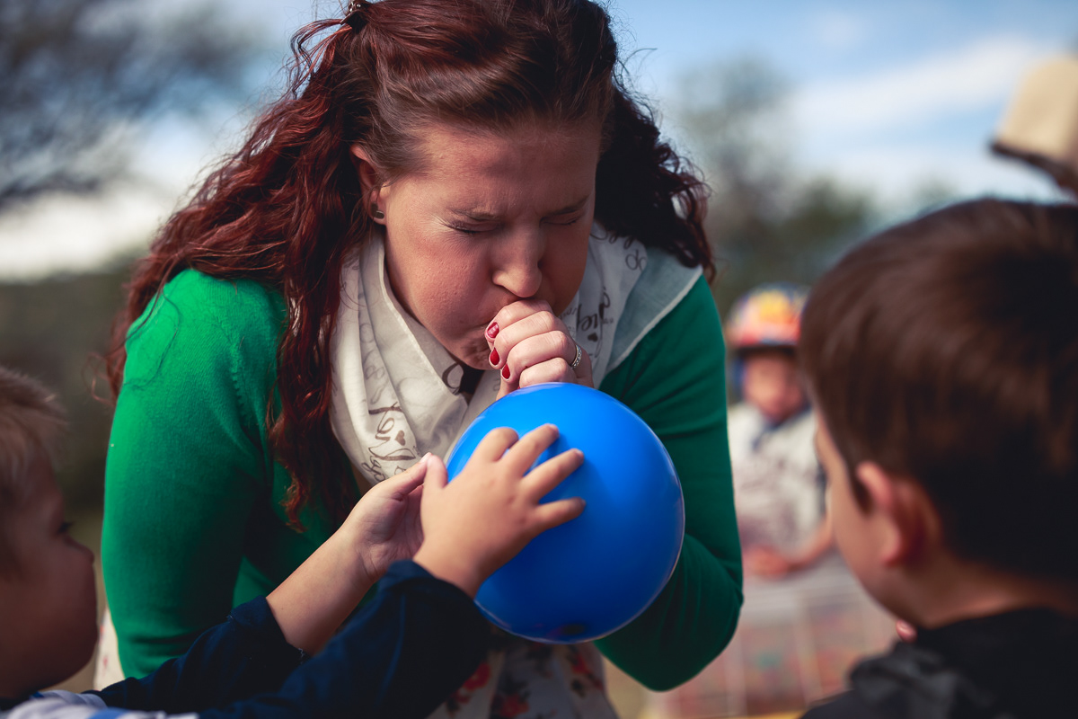 Lady blowing up a blue balloon for kids