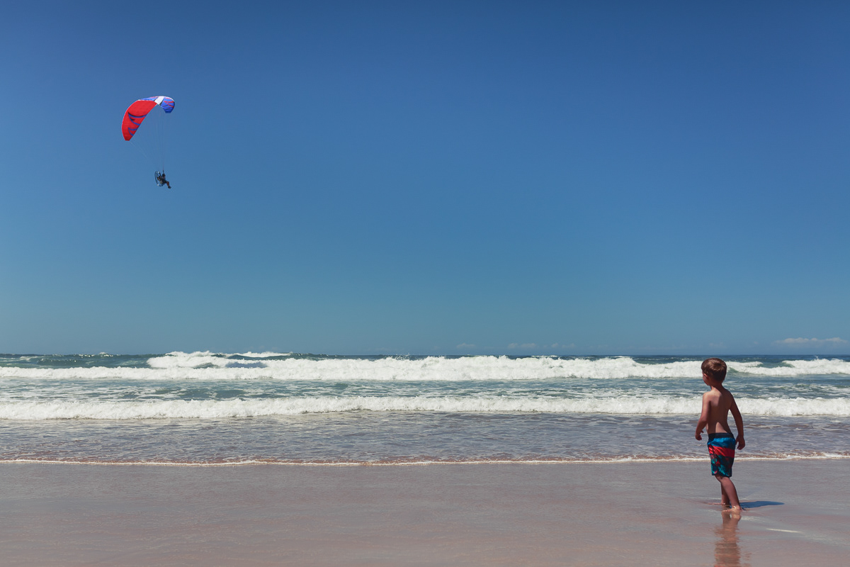 Boy on beach looking at a kite