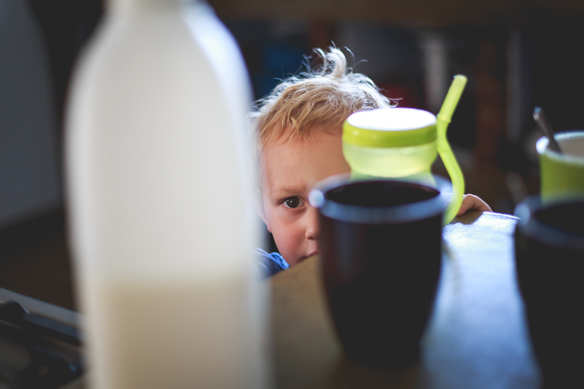 Boy peeking through cups and a bottle of milk