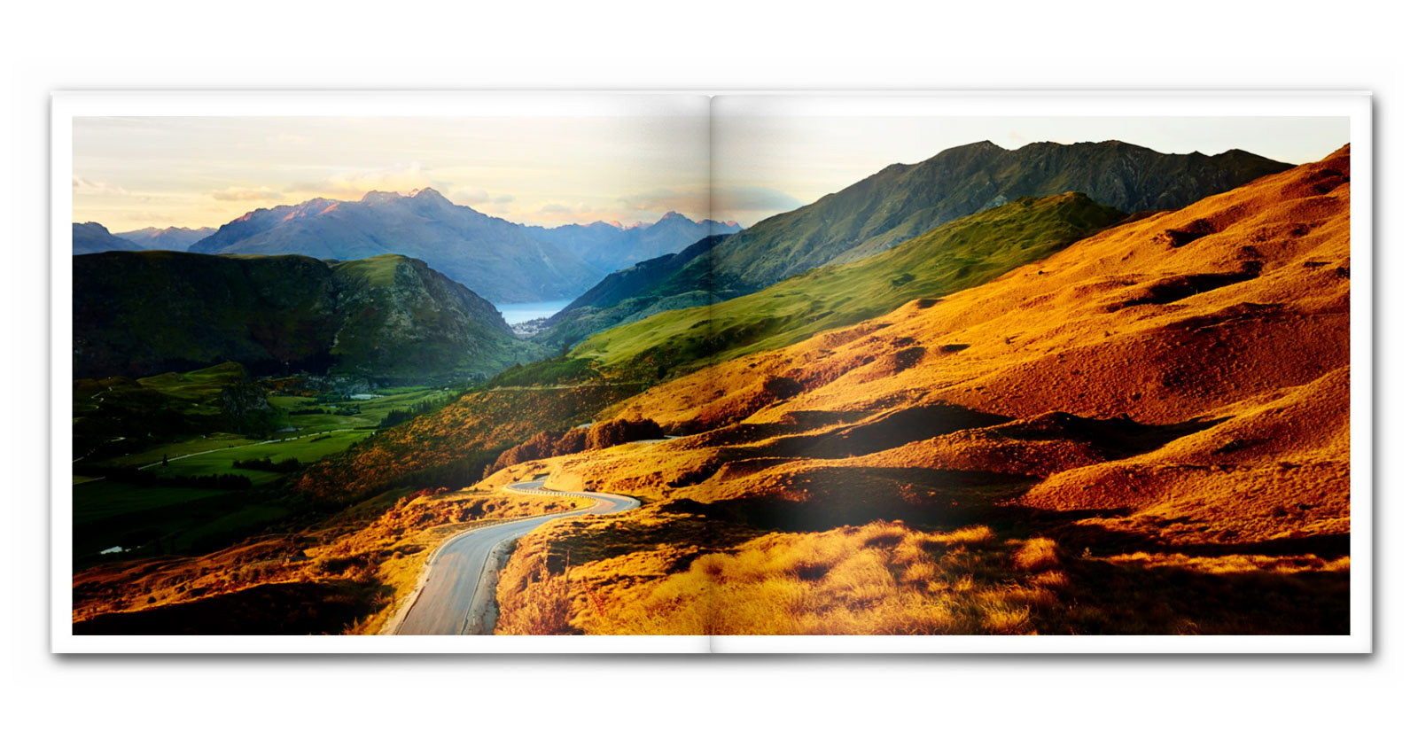 Mountain road in New Zealand leading through the landscape toward a lake in the distance..