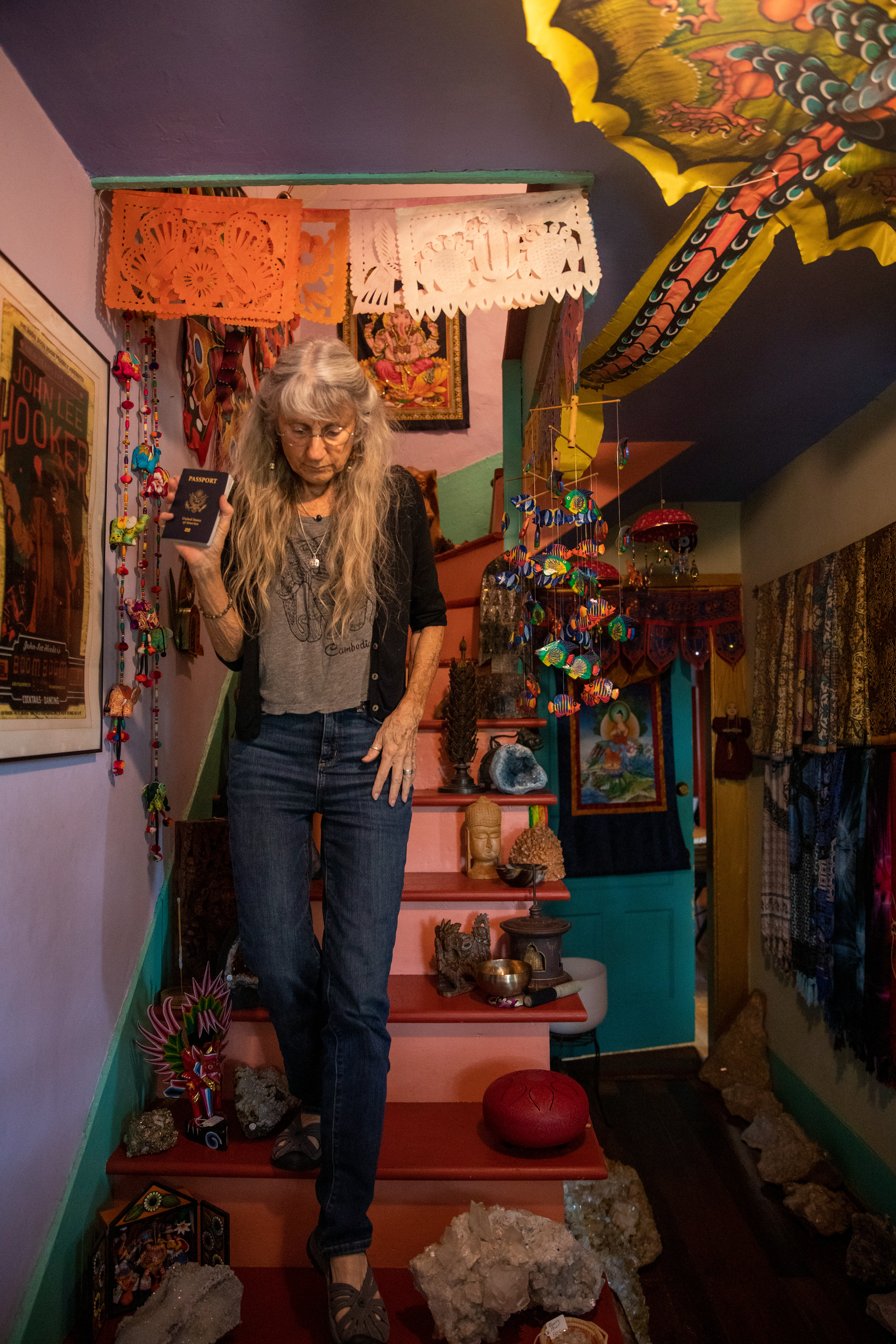 Jo Merkle, 69, comes down the front stairs with her passport for an upcoming trip at Beads and Things, Athens, Ohio on September 9, 2022.