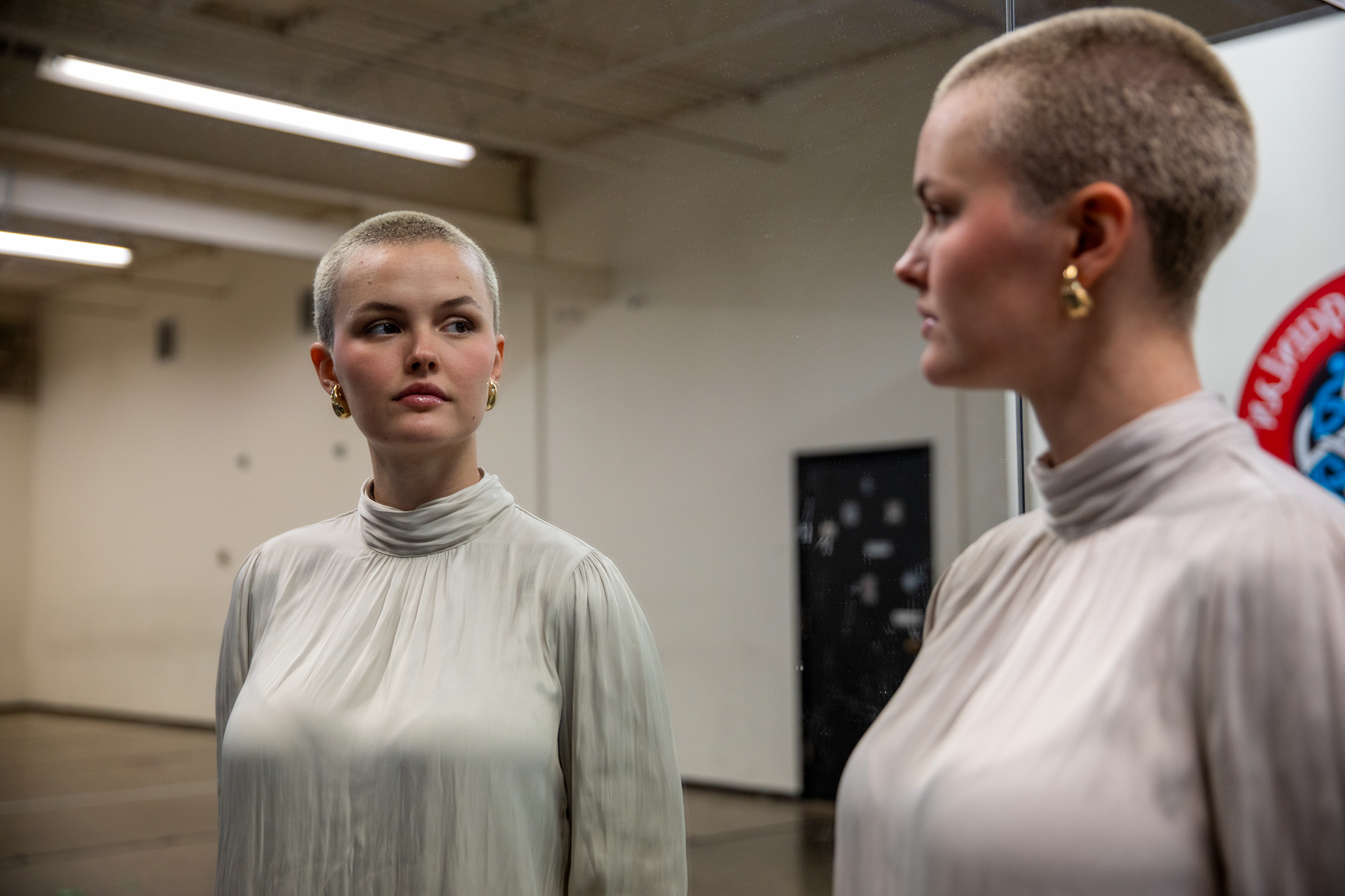 Seana Isaac, 23, of South Whitehall Township, sees her reflection as she talks Wednesday, May 15, 2024, about her diagnosis with diffuse midline glioma of the pons, a rare pediatric brain cancer, at O’Grady Quinlan Academy of Irish Dance in Easton.