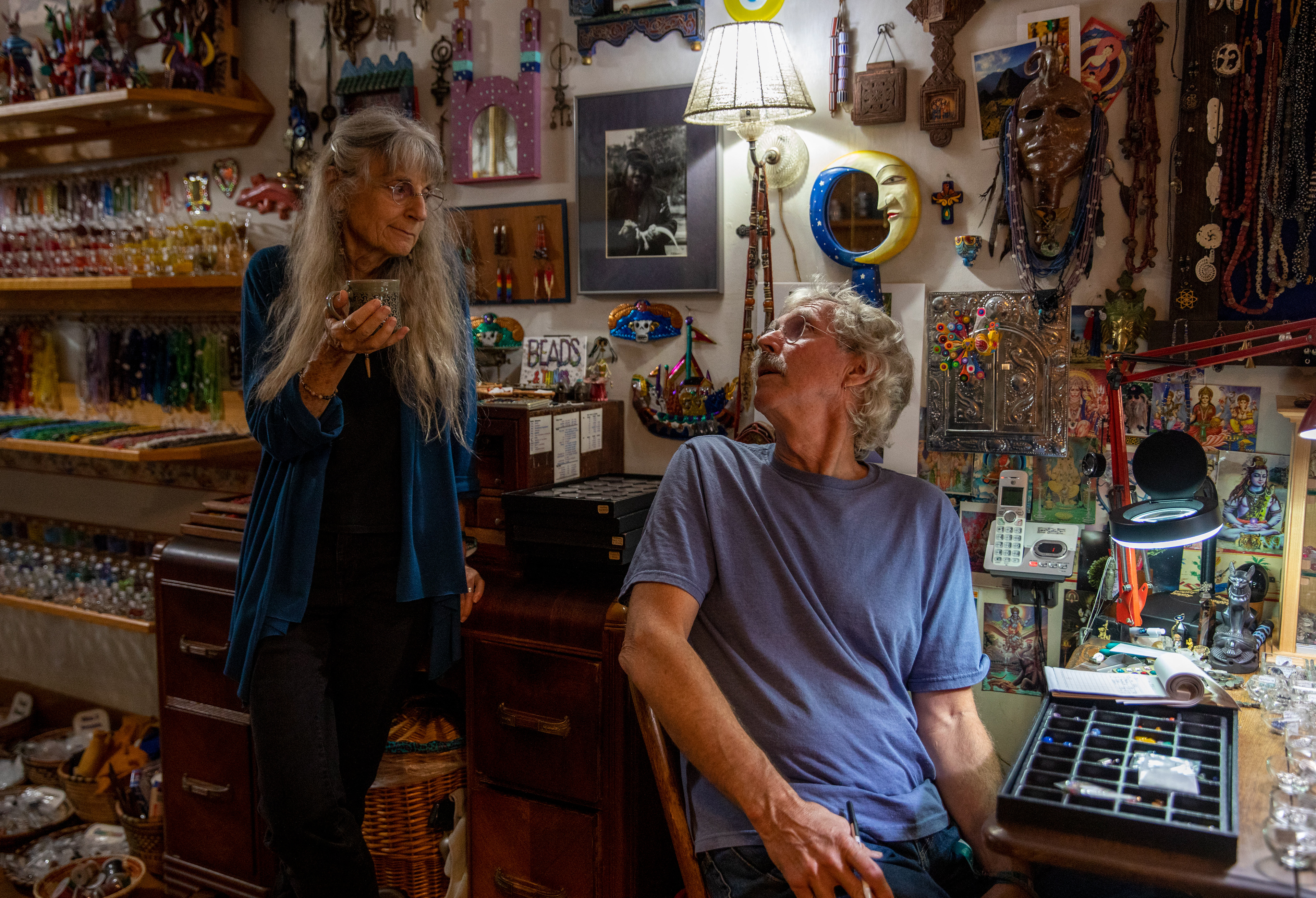 Phil Berry, 67, and Jo Merkle, 69, discussing their plans for the Nelsonville Music Festival as Phil adds up beads for a customer at Beads and Things, Athens, Ohio, on September 3, 2022.