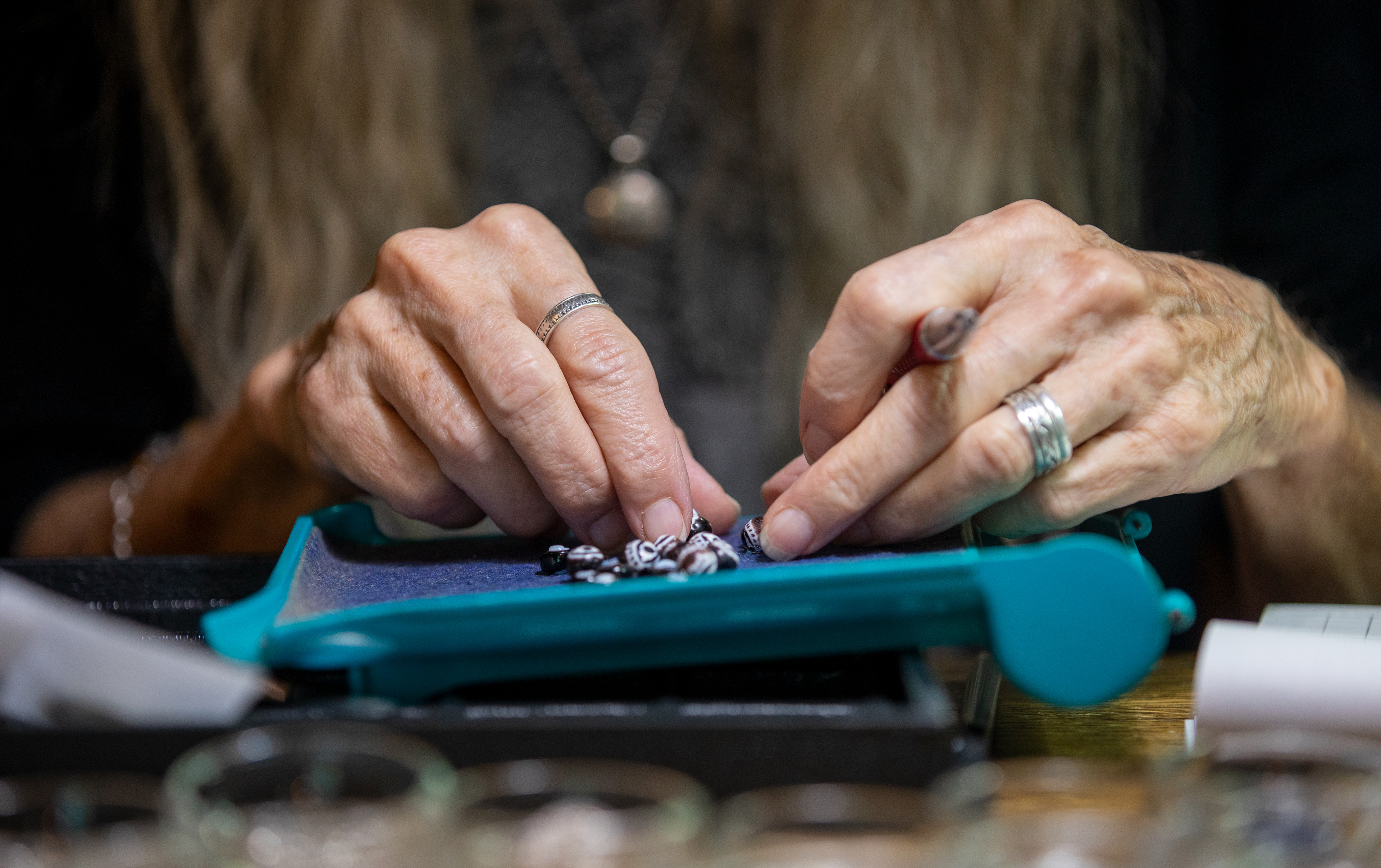 Jo Merkle's hands as she counts beads for a customer at Beads and Things, Athens, Ohio on September 9, 2022.