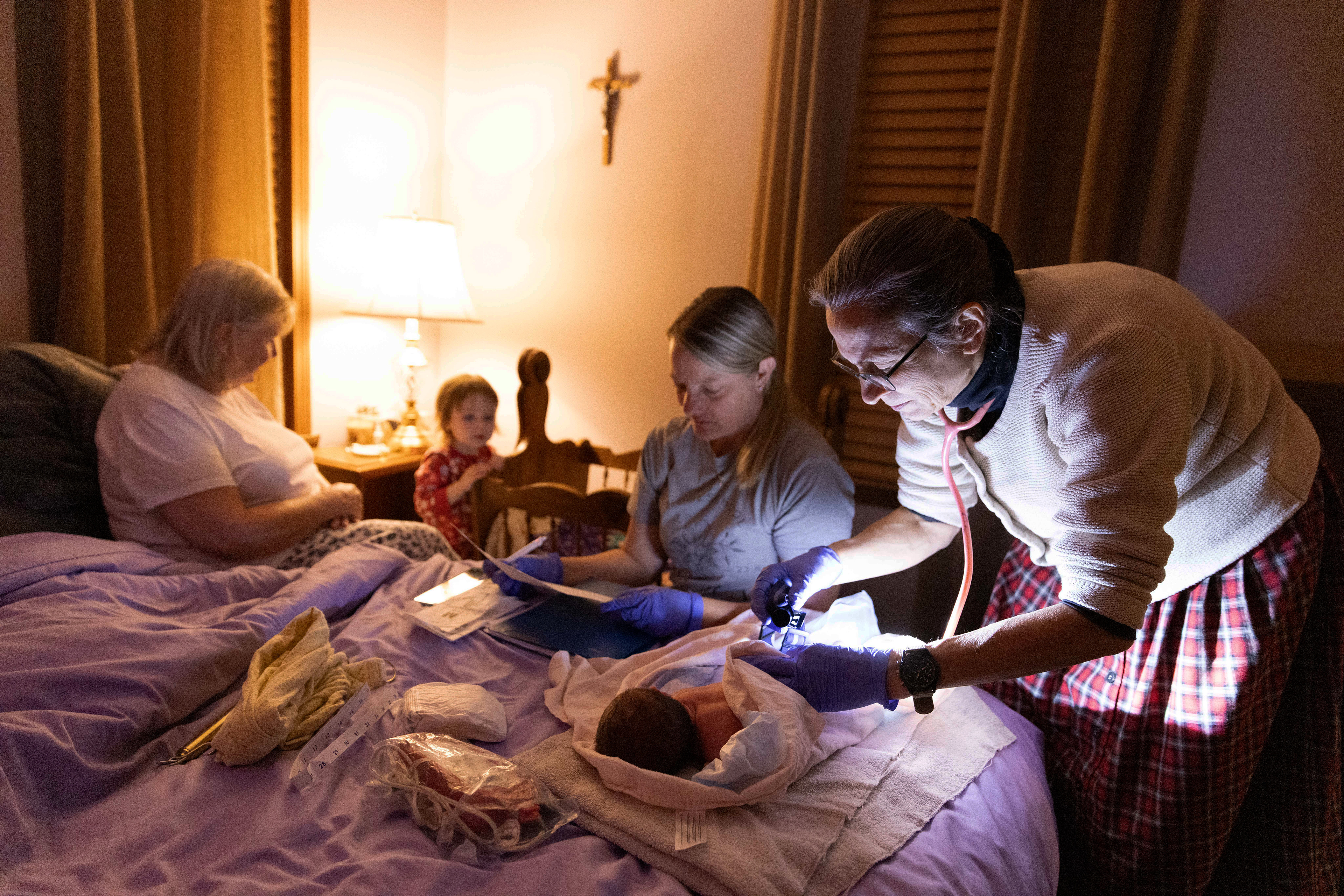 Kristina Muehlhauser, a 37-year certified professional midwife, performs a physical examination on Valerie, a newborn baby, as she lies on her parents’ bed after the homebirth of Megan Mascari at her home in Circleville, Ohio, Oct. 17, 2024.