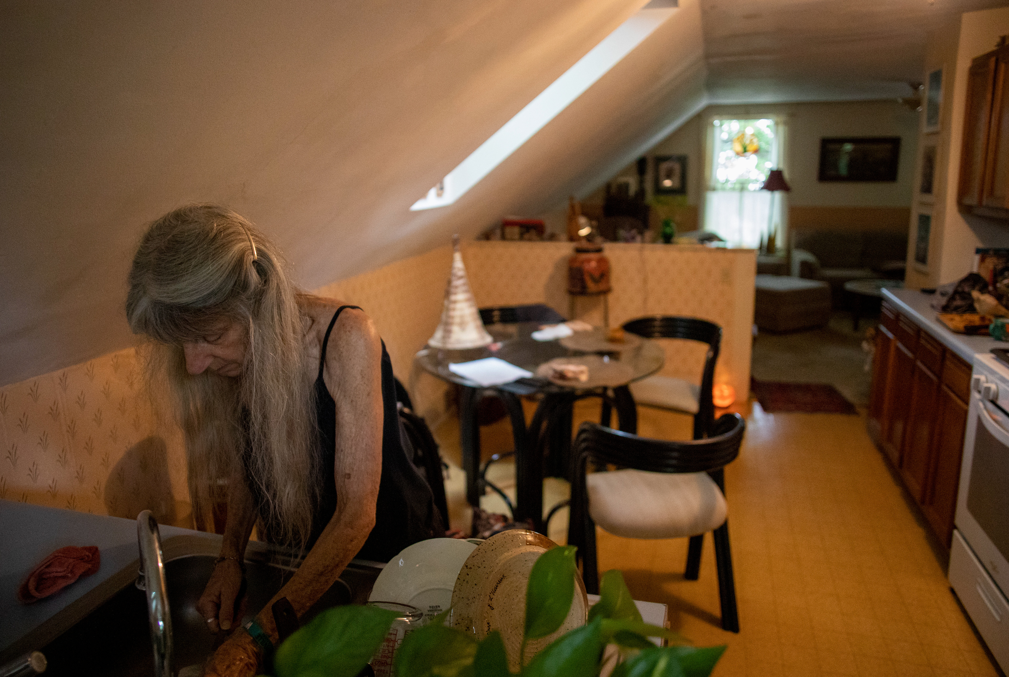 Jo Merkle, 69, washing the dishes after breakfast in her apartment above the bead store at Beads and Things, Athens, Ohio on September 3, 2022.