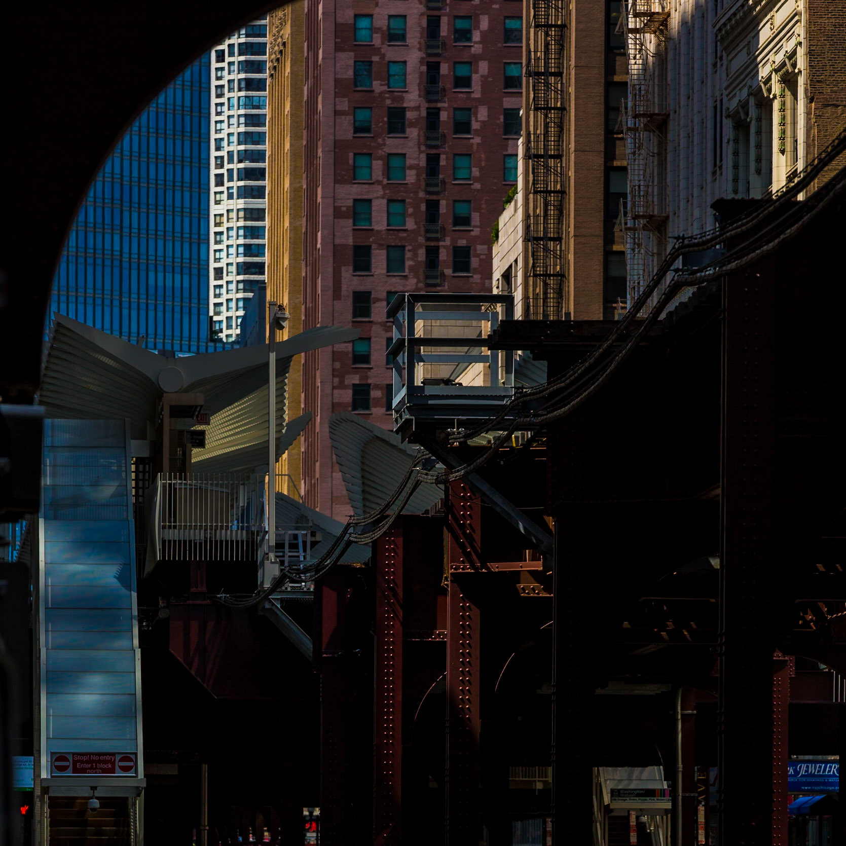 State &amp; Lake elevated CTA station. Late afternoon sun creates a rich brocade of iron trestles, glass &amp; aluminum winged overhangs, and the façades of historical &amp; modern skyscrapers alike in downtown Chicago.