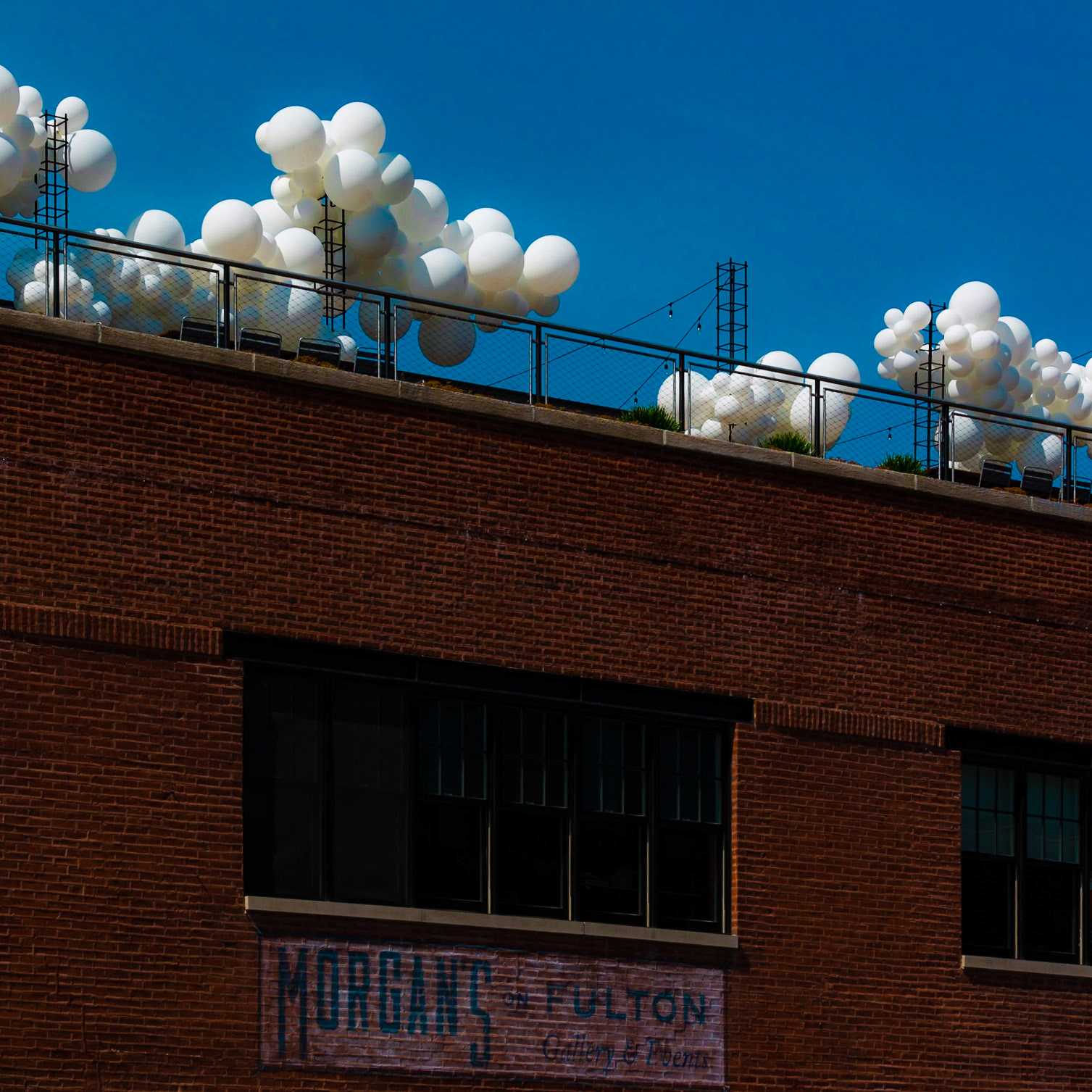 Little balloon on clouds brighten up a brick building.