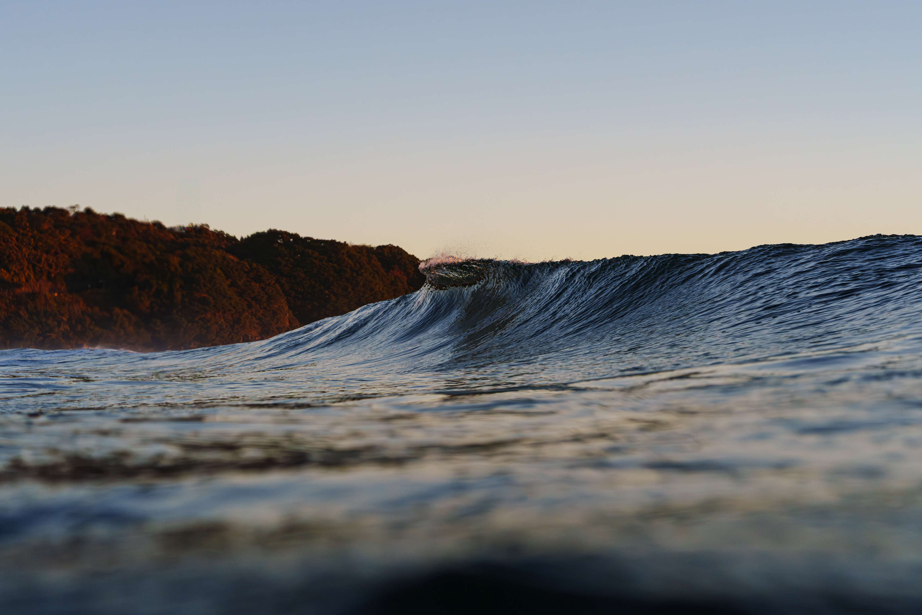 前日雨模様だけど胸〜肩までサイズが上がっていた。翌日の波高予報も前日より強まる予報、天気予報も晴天なので急遽向かった。道中橋の上が強風で心配だったが朝イチは影響はなかったが腰〜胸にサイズダウン。朝イチは潮が多い時間帯だったけど朝陽の光と波が撮りたかったので日の出と同時に入った。ビーチは裸足で歩くと冷たさで痛くなるぐらい冷え込んでいたけど海水は暖かくウエットは3mmで十分だった。ハウジングに入水しないかインサイドで何度もチェックしてアウトに向かった。  2025/12/22　Kochi (1/1250sec F5.0 ISO800 40mm)