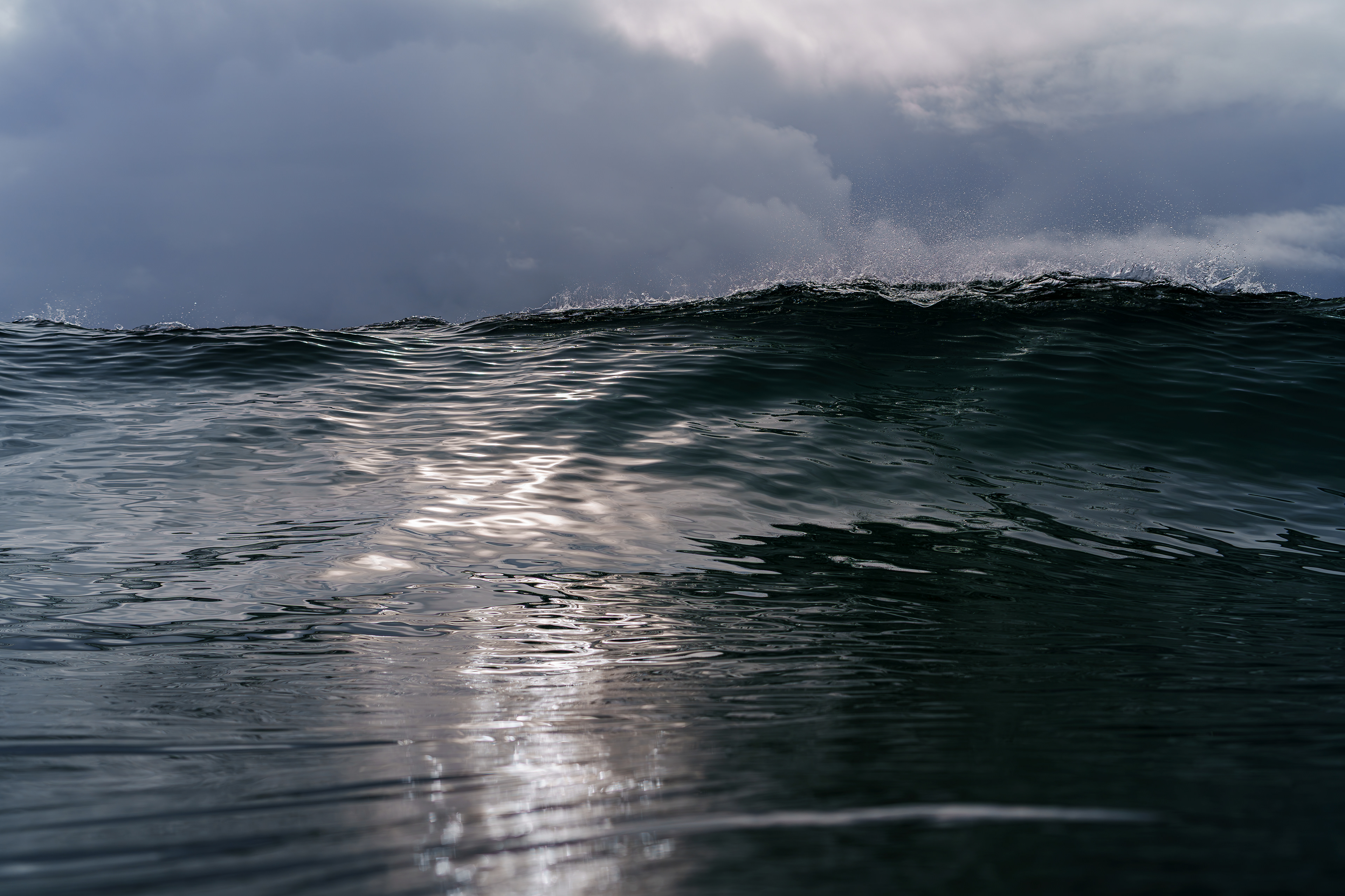 ほんとうにころころ変わる天気。先程までは青空が見えていたが薄暗い空模様に。ピークがブレイクする瞬間を撮影していると雲の隙間から陽の光が入りフェイスを輝かせた。ブレイクする側はウネリが光を遮断し暗く対照的な写真が撮れた。 06/25/2025　Shikoku