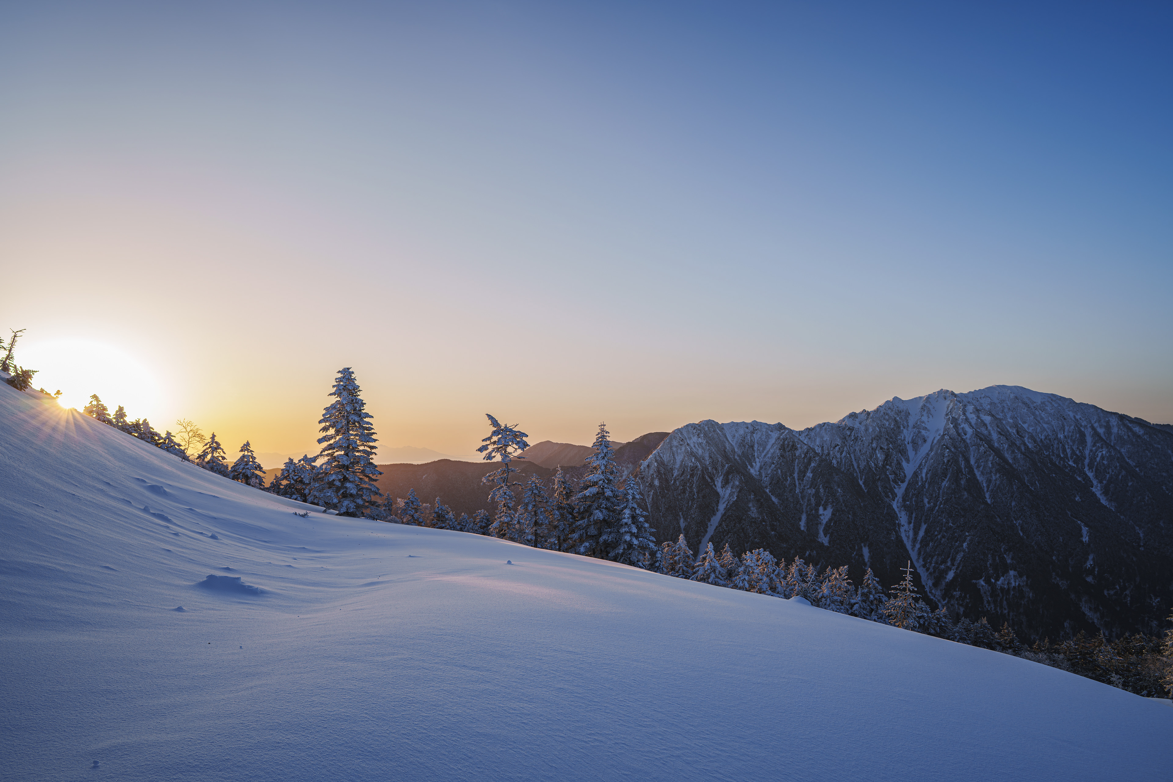 『wrap 』 前日は雪が降り続きガスっていた西穂高。テントの中で夕方には少し景色が見れるかと耐え忍んでいたけどその期待は報われず...深夜に目が覚めると風は弱まり、外を覗くと空は星が輝いていた。急いでテントを撤収し登り始めると太陽が暖かくすべてを包み込んでくれた。  3/12/2025　西穂高