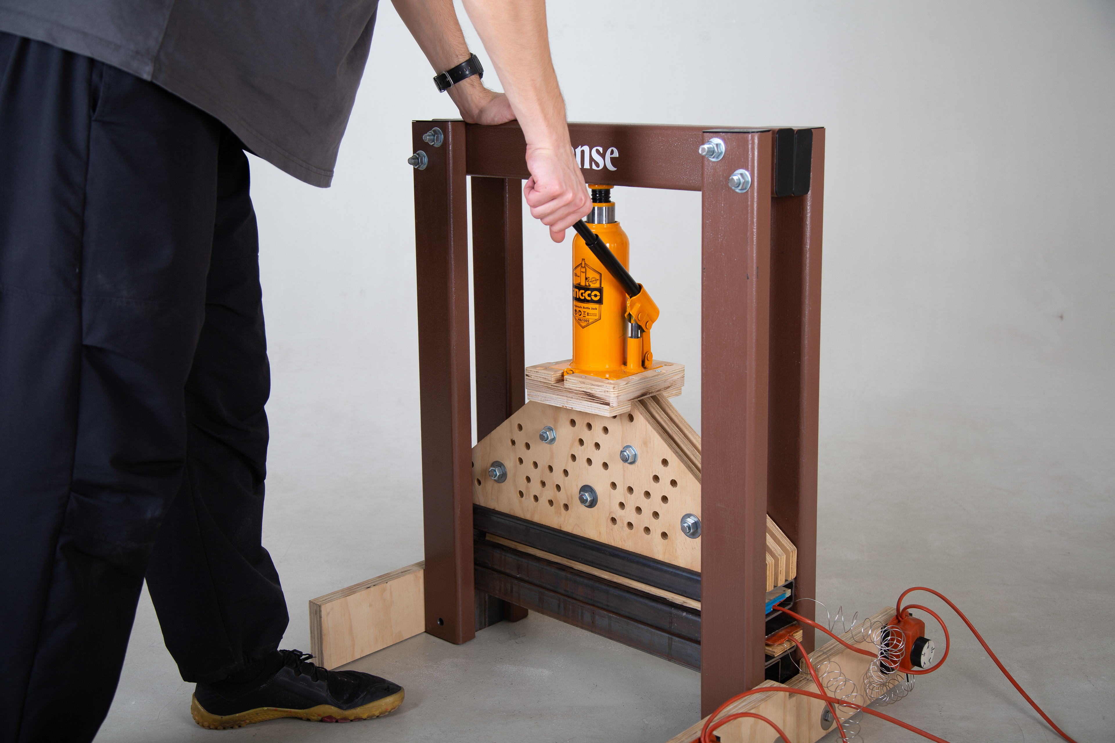 Compression through a manually operated 10T hydraulic bottle jack.