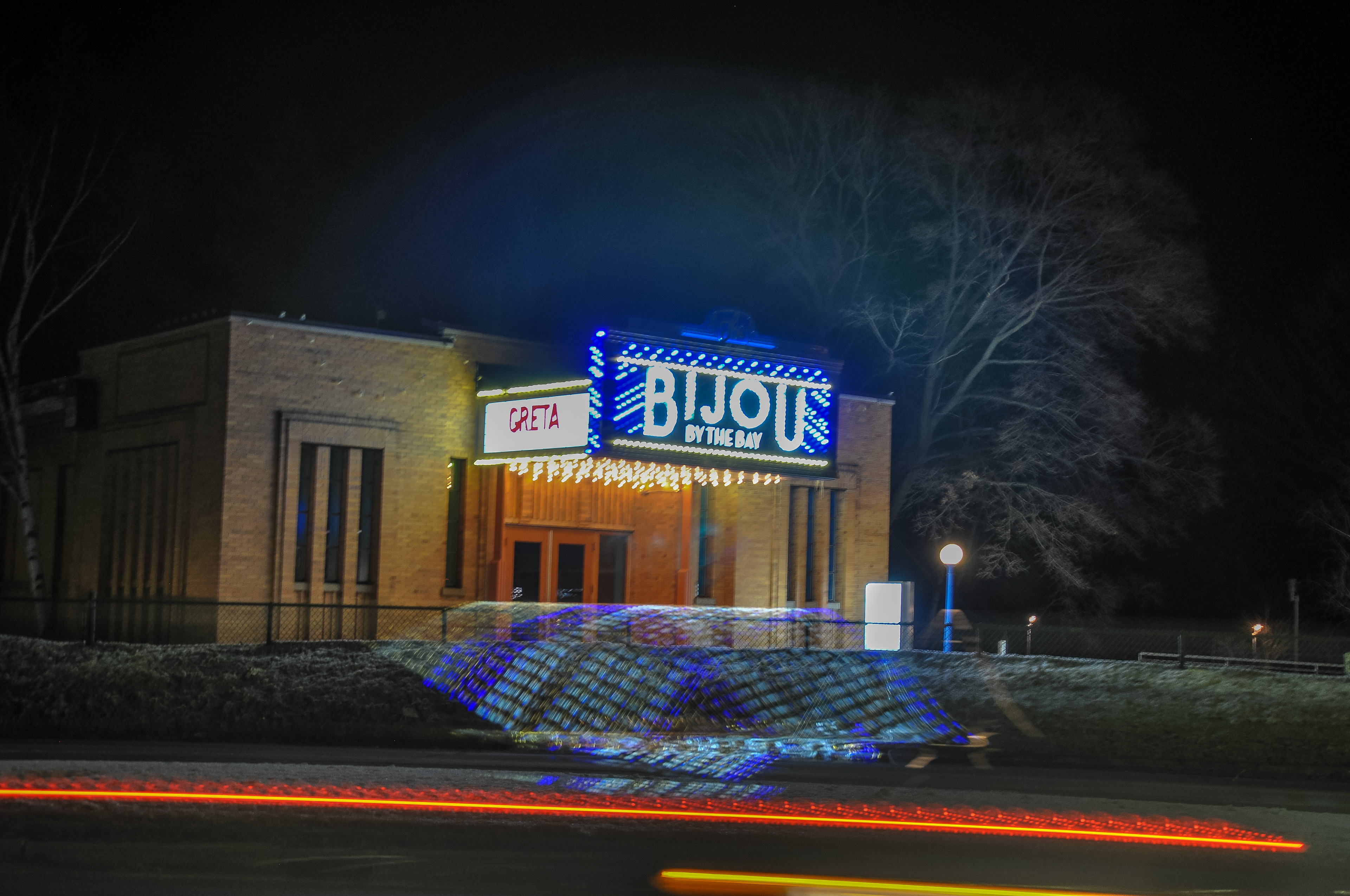 Long exposure shot of a car driving by a theater