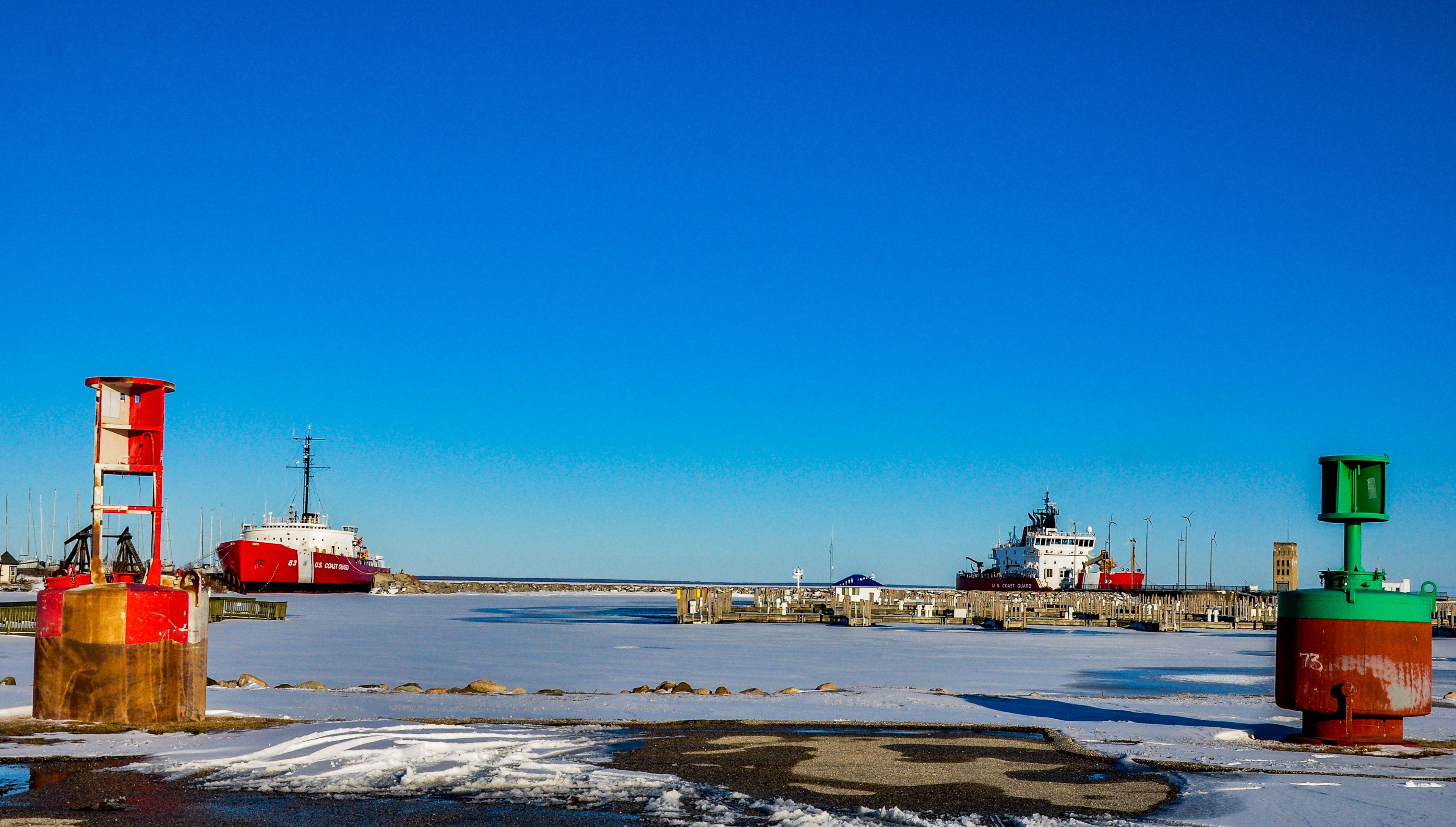 Retired USCGC Mackinaw (WAGB-83) to the left while the commisioned USCGC Mackinaw (WLBB-30) does work at the State Harbor on the right; Mackinaw City, MI. March 2020
