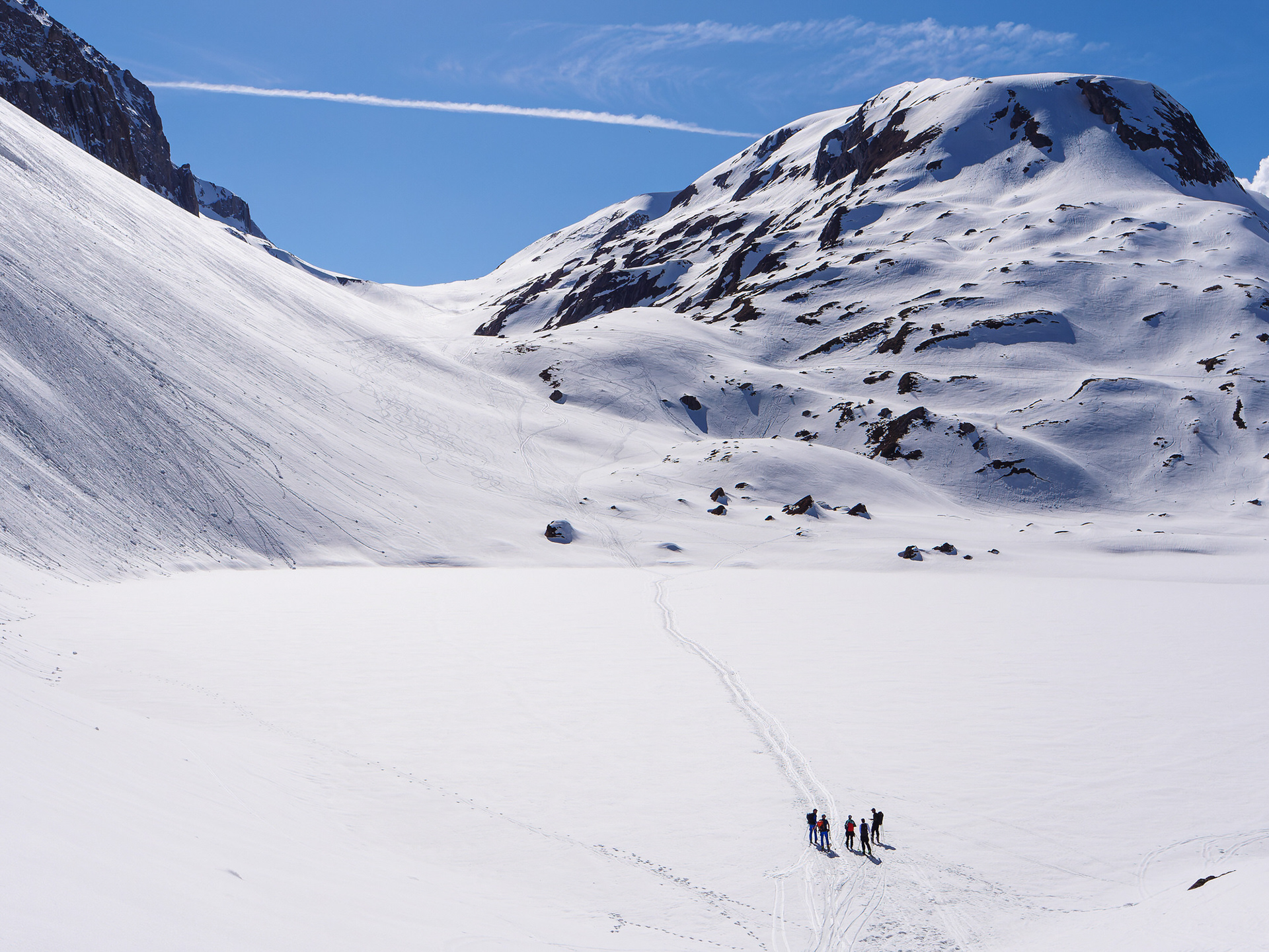 Ski tourers taking a break while crossing a frozen lake in the Swiss Alps.