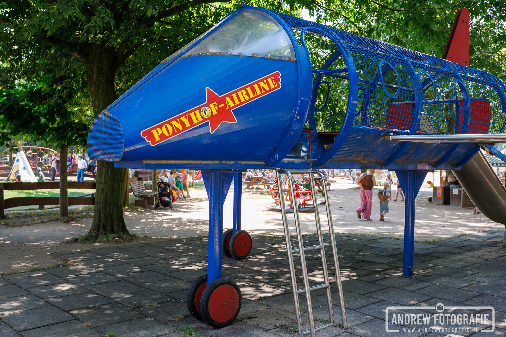 Blauw speelgoedvliegtuig met de tekst Ponyhof Airline in de speeltuin.