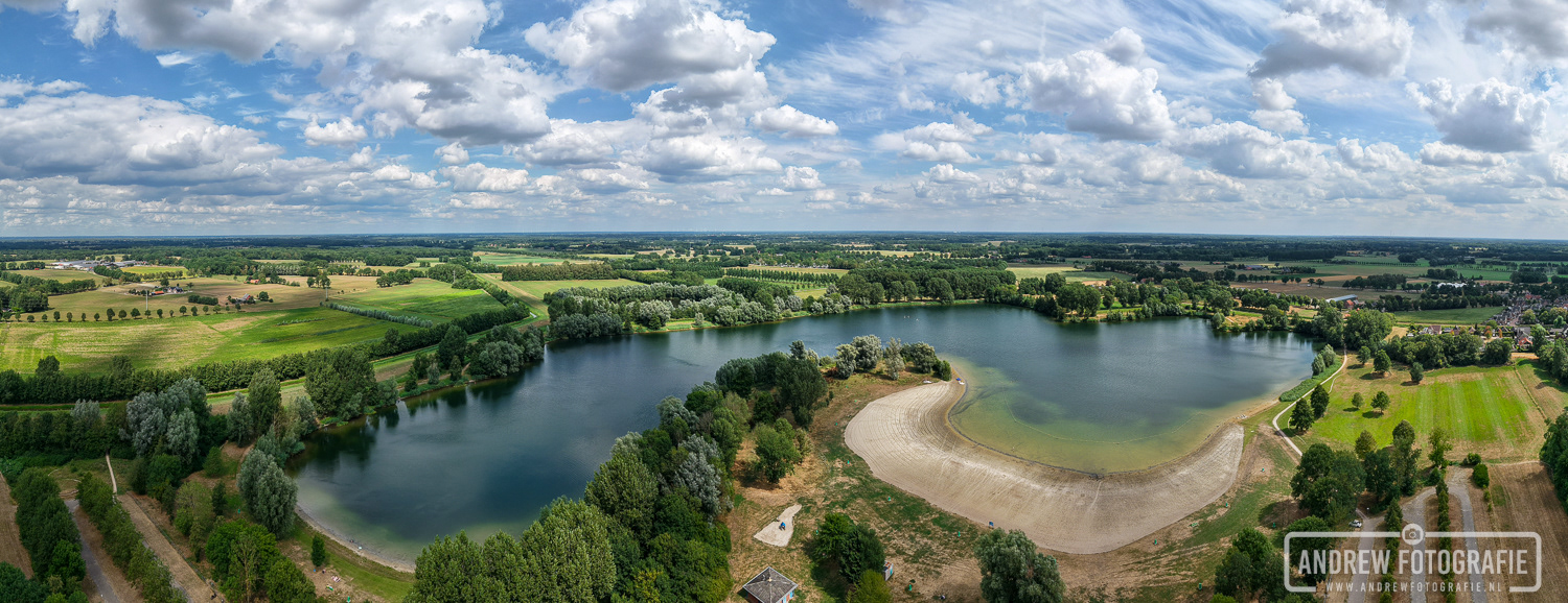 Luchtfoto van de droogte bij de Slingeplas in Bredevoort met een gezakt waterpeil en verdord gras in de Achterhoek.