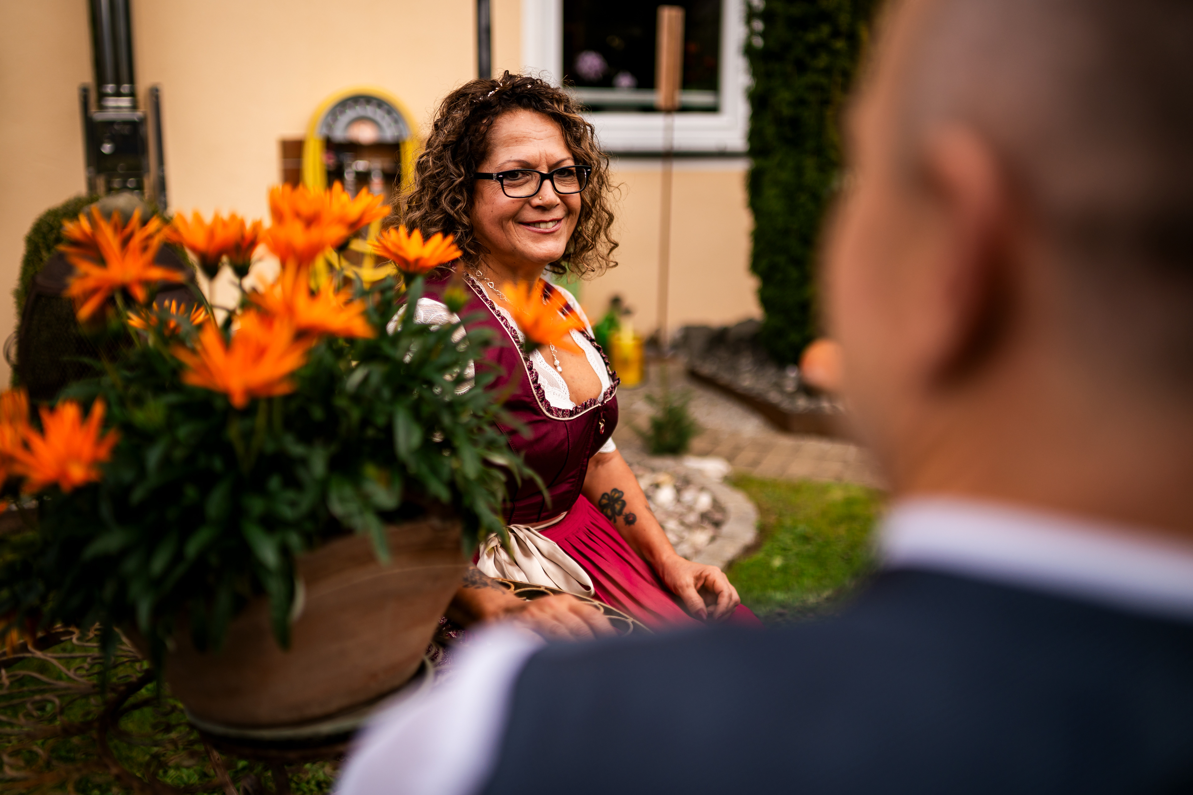 Bräutigam lächelt seine Braut im Garten des Elternhauses in Rot an der Rot an. Start der Trachtenhochzeit, fotografiert von MFUCHSLOCH Fotografie & Videografie.