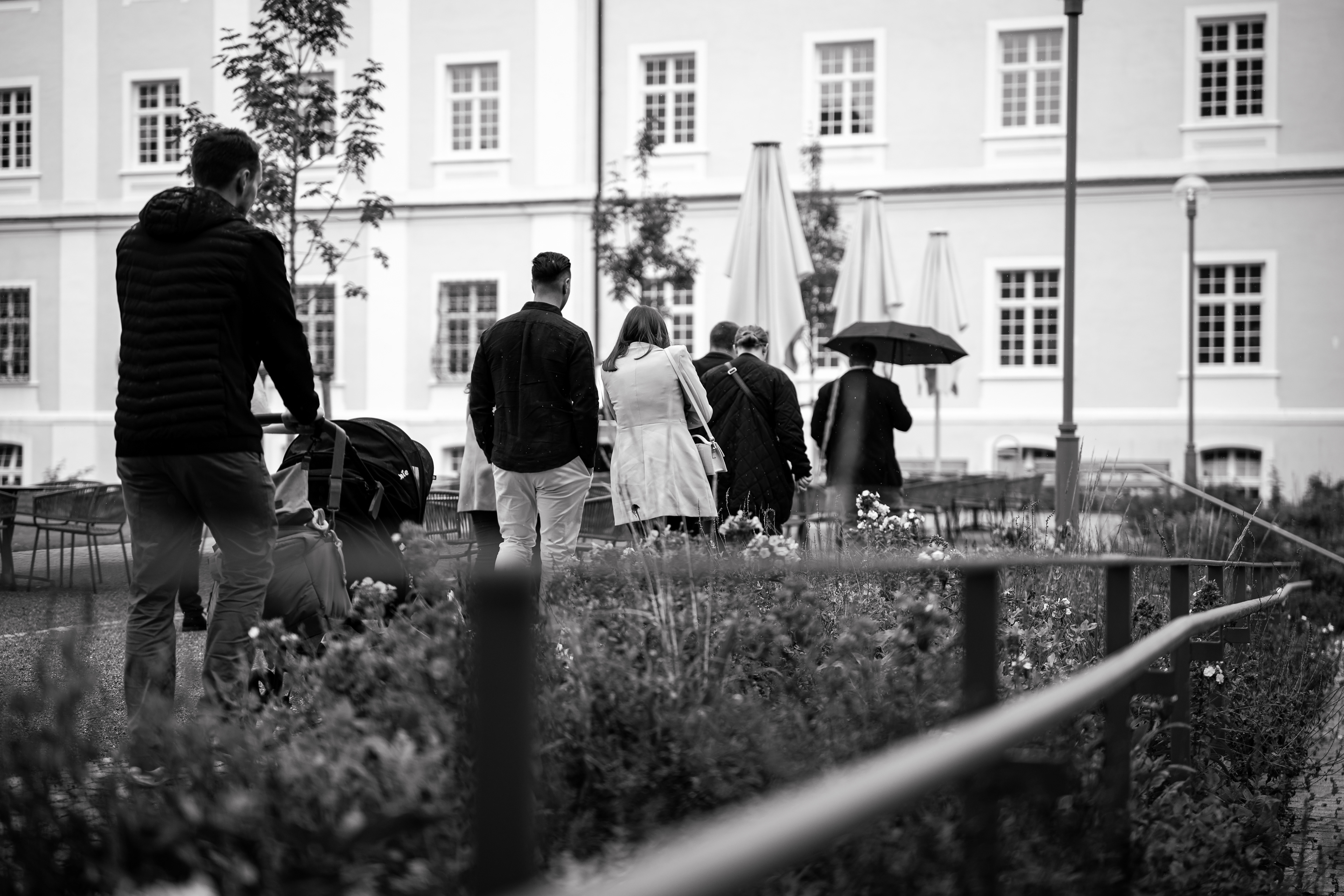Schwarz-Weiß Aufnahme der Hochzeitsgesellschaft beim Spaziergang durch die Klosteranlage in Bad Schussenried. Teil einer Hochzeitsreportage von MFUCHSLOCH.