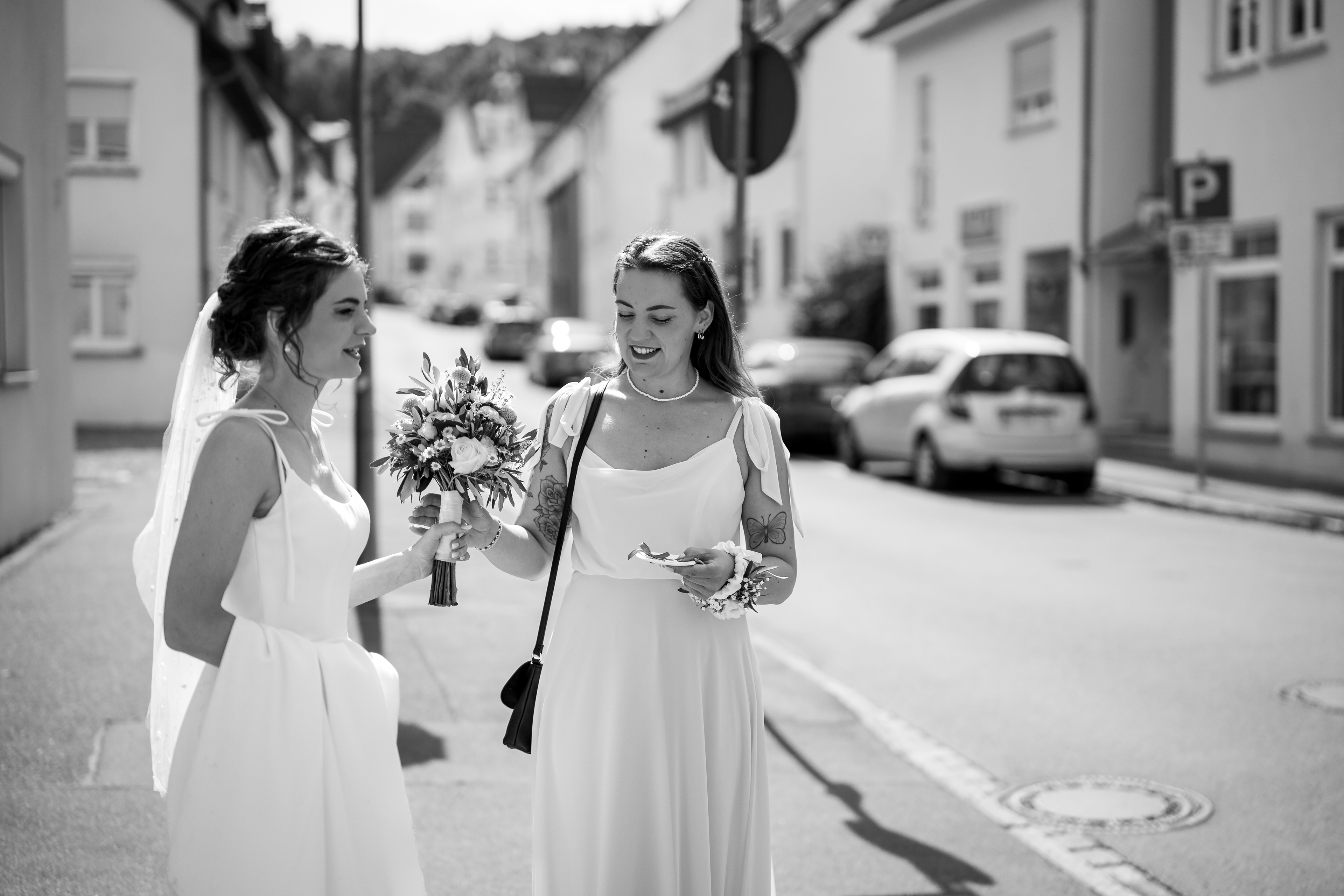 Braut Melanie und ihre Trauzeugin lachen herzlich miteinander auf der Straße. Ungezwungener Moment der Hochzeitsreportage in Weingarten von MFUCHSLOCH Fotografie & Videografie.