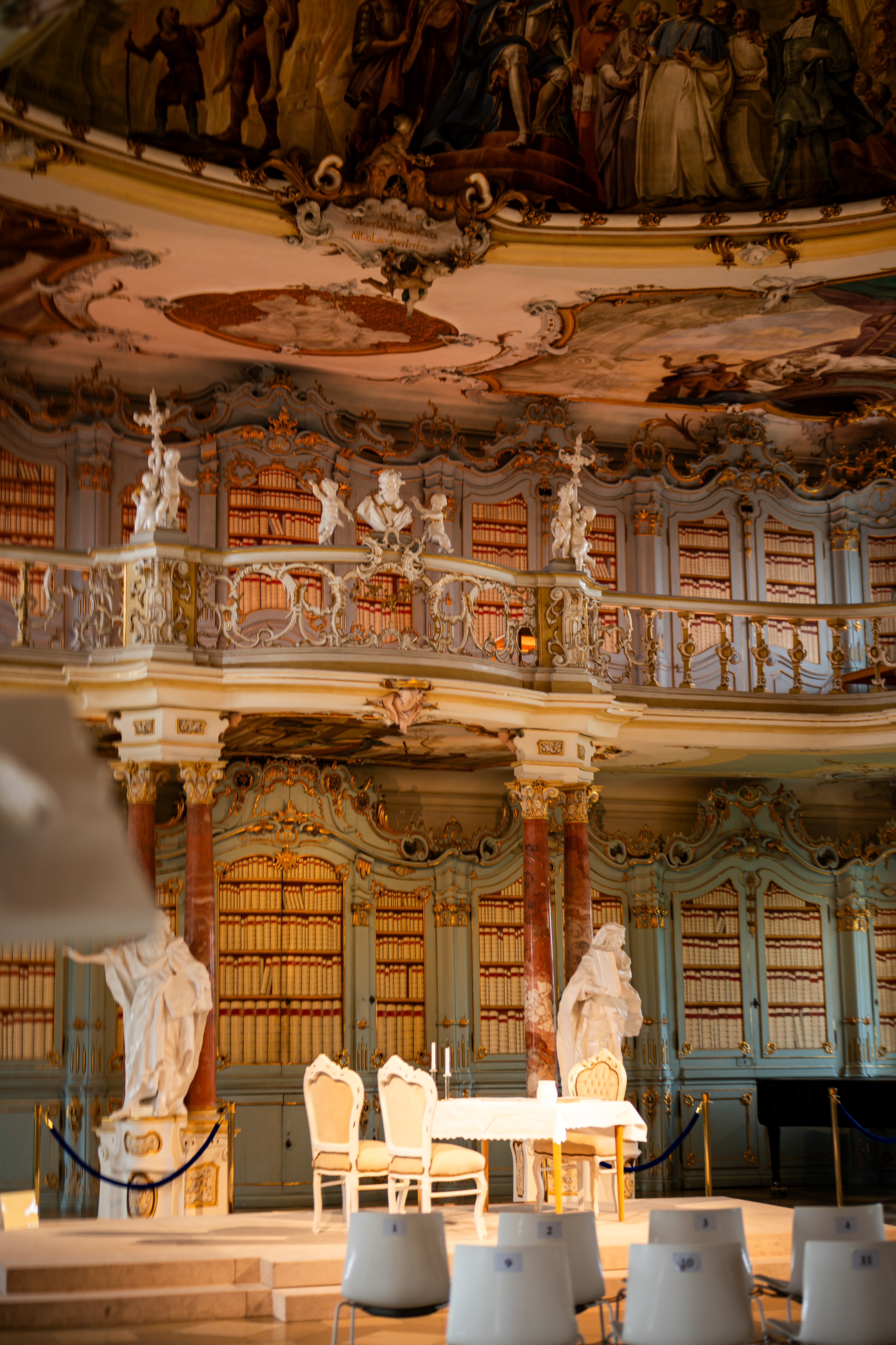 Feierliches Setup für eine standesamtliche Trauung im prunkvollen Bibliothekssaal des Klosters Bad Schussenried. Traumhafte Hochzeitslocation in Oberschwaben mit historischer Architektur, professionell festgehalten als Hochzeitsreportage von MFuchsloch Fotografie.