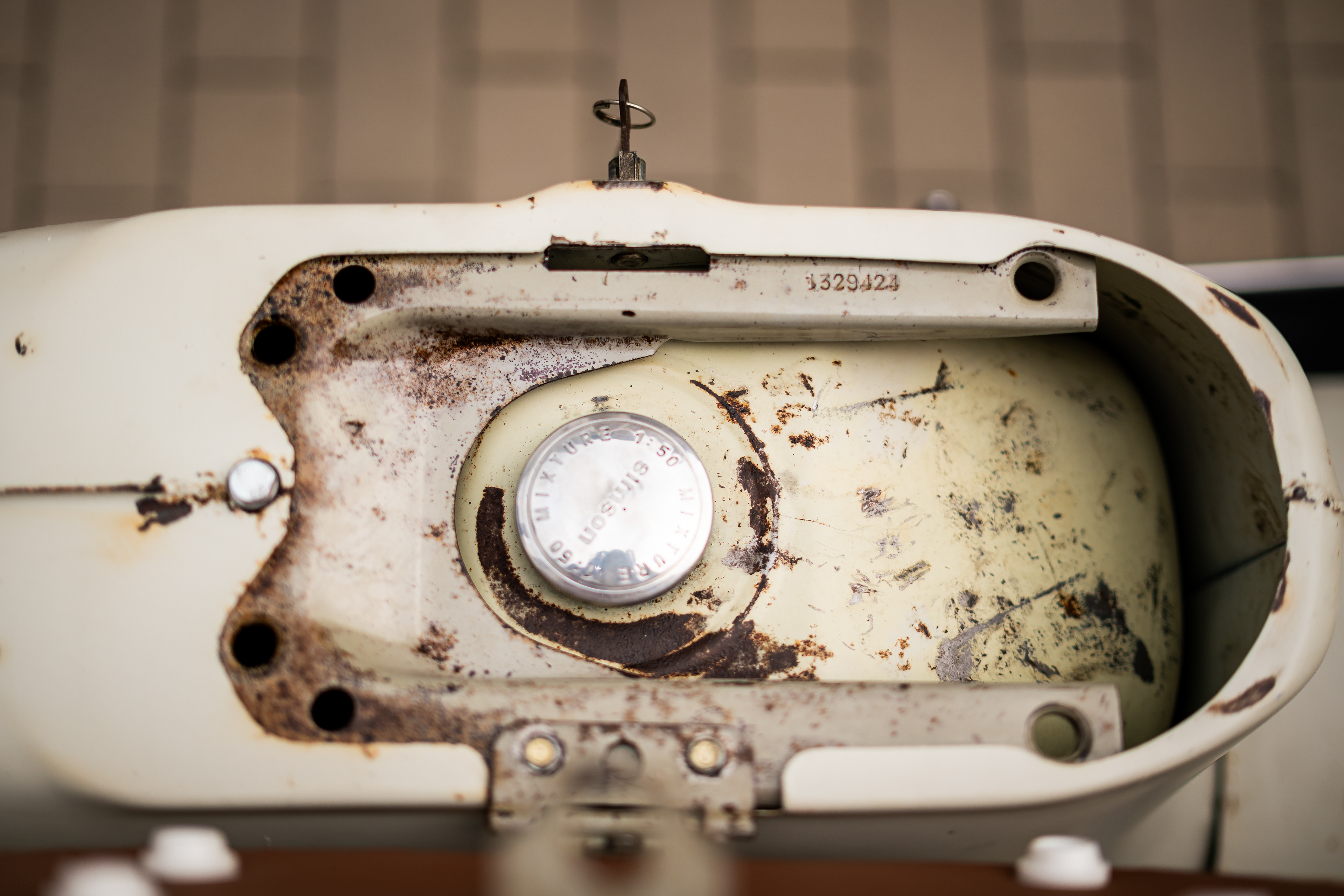 Blick von oben auf den originalen Simson-Tankdeckel mit Mixture 1:50 Aufschrift im rostigen Rahmen. Dokumentarische Oldtimer-Restauration fotografiert in Bad Buchau.