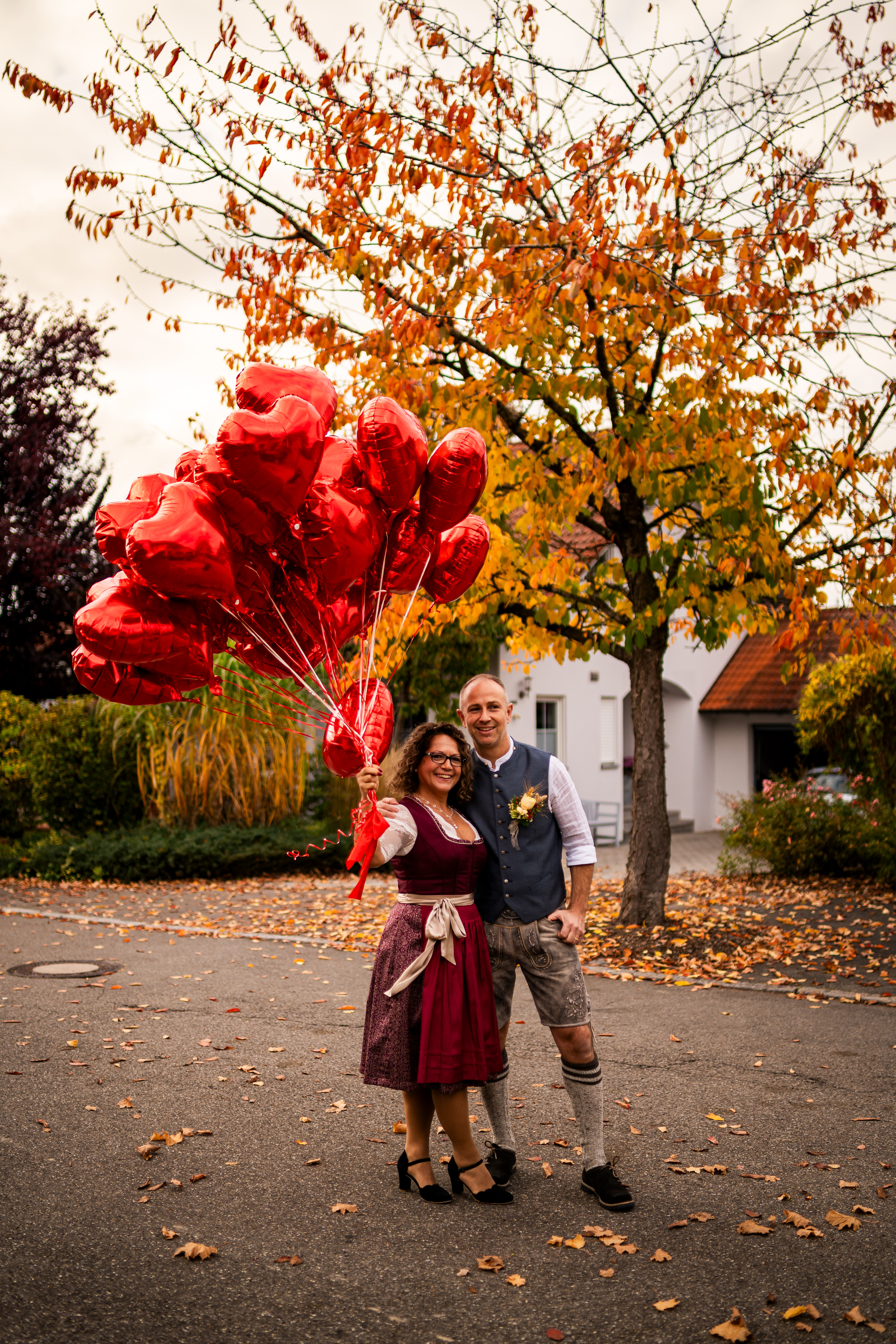Brautpaar in Tracht mit Luftbalon . Herbstliche Hochzeitsfotos in der Natur von MFUCHSLOCH Fotografie & Videografie.