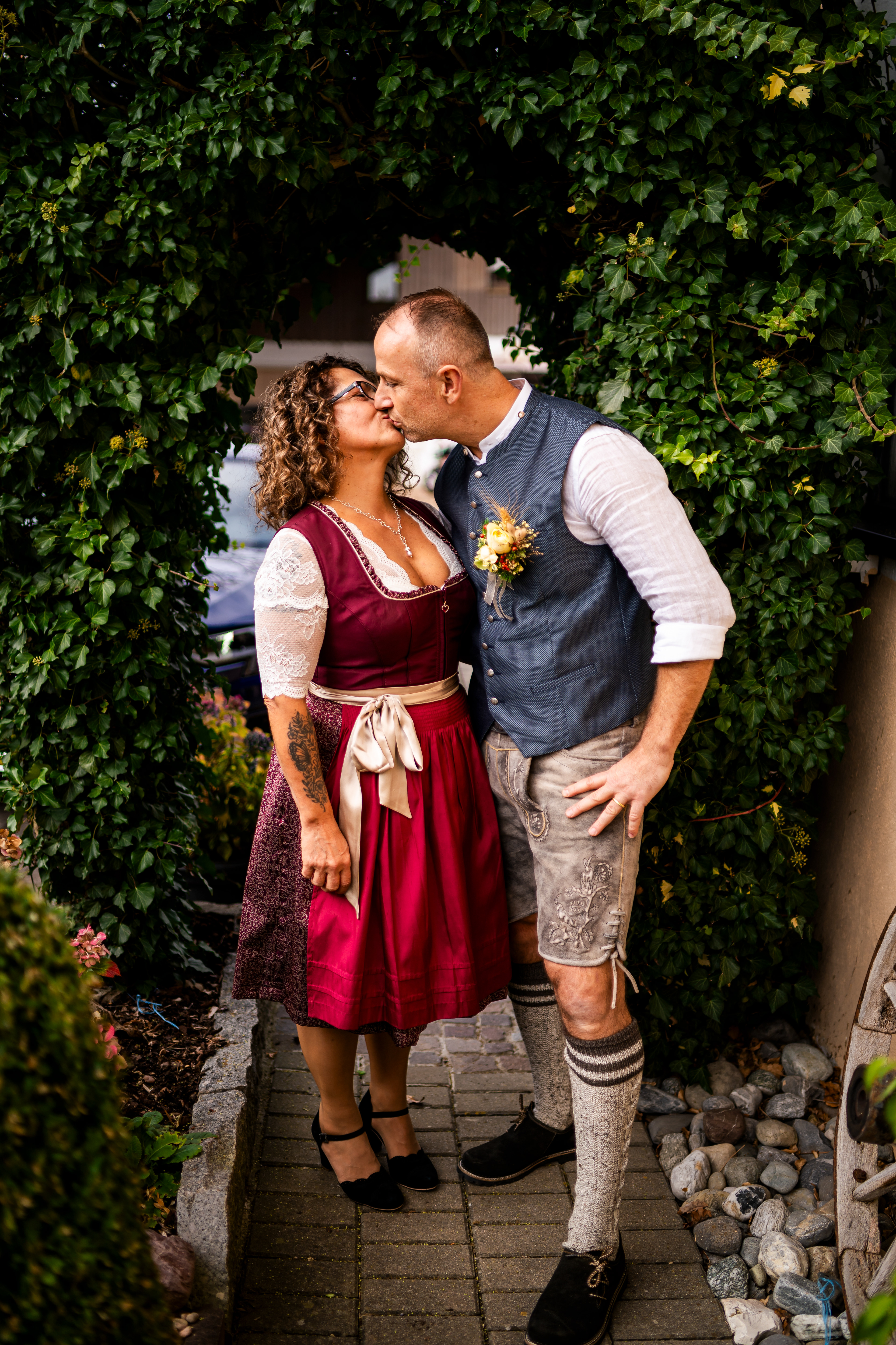 Romantischer Kuss des Brautpaares in Dirndl und Weste. Emotionale Hochzeitsfotografie in Rot an der Rot von MFUCHSLOCH Fotografie & Videografie.