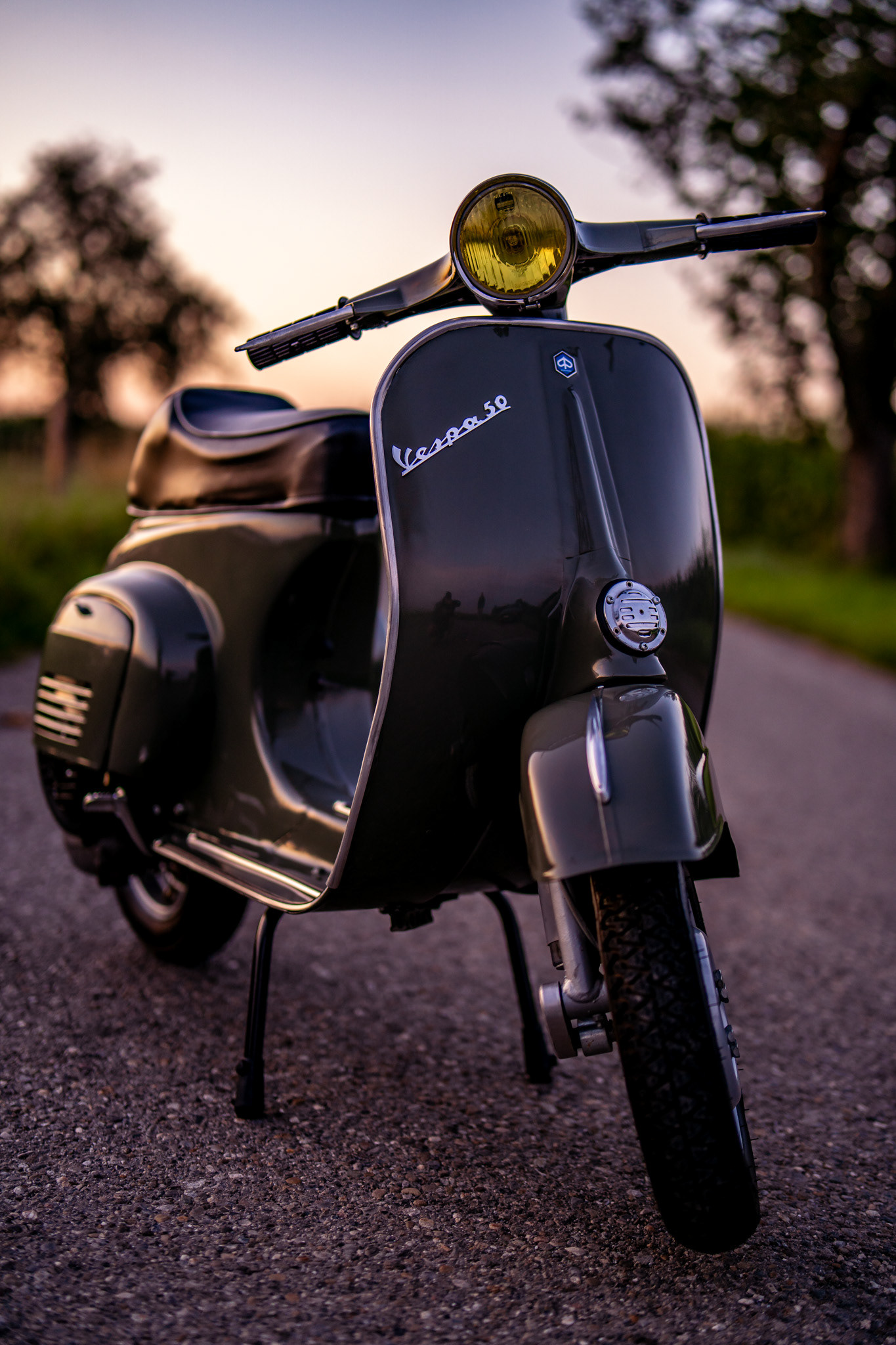 Klassische Vespa 50 Special in Aventurin Grün Metallic auf einem Feldweg mit Sonnenaufgang in Oggelshausen am Federsee während der Golden Hour. Professionelle Fahrzeugfotografie und Automotive Art von MFuchsloch Fotografie & Videografie aus Oberschwaben.
