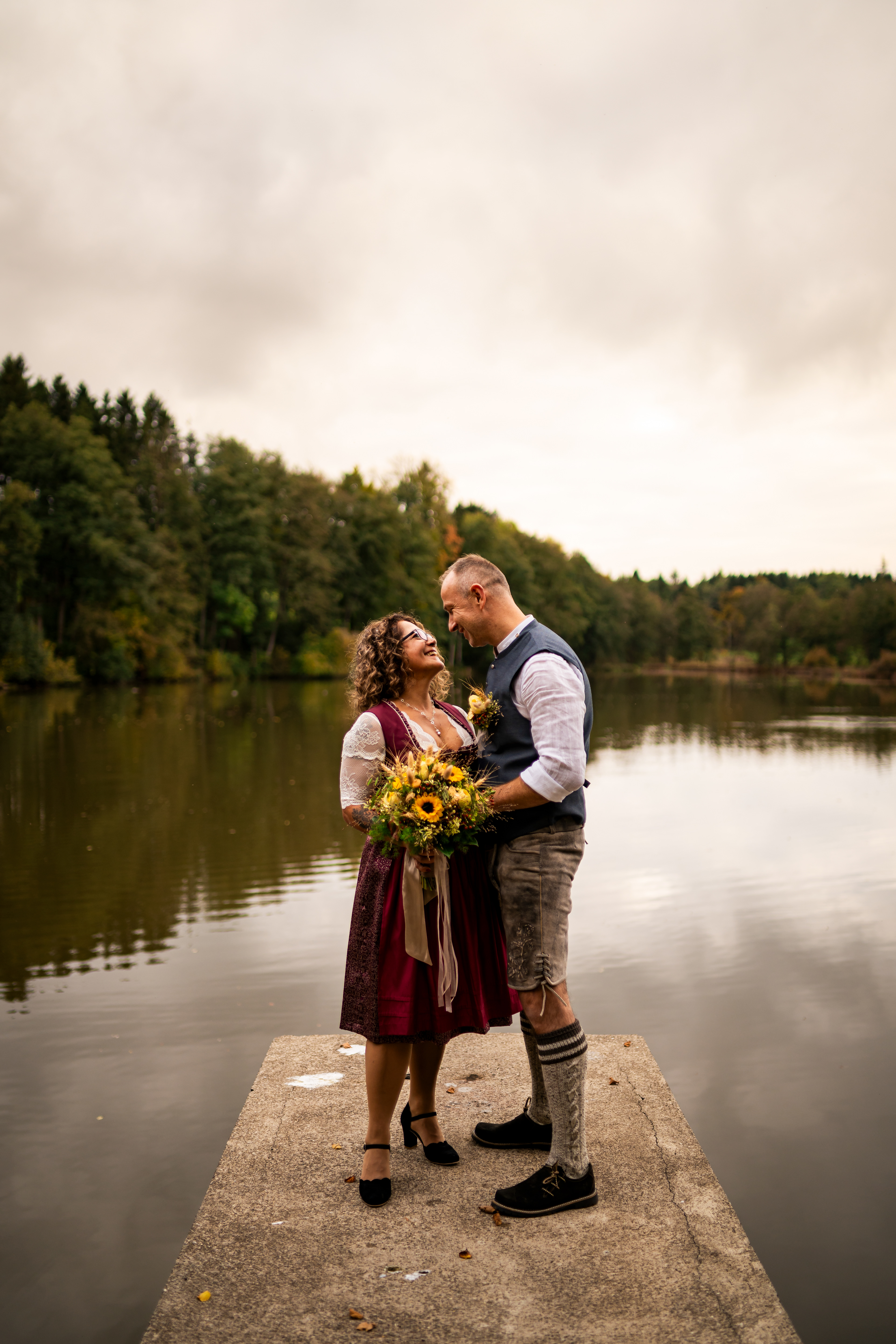 Brautpaar in Tracht genießt die Zweisamkeit am Seeufer. Herbstliche Hochzeitsfotos in der Natur von MFUCHSLOCH Fotografie & Videografie.