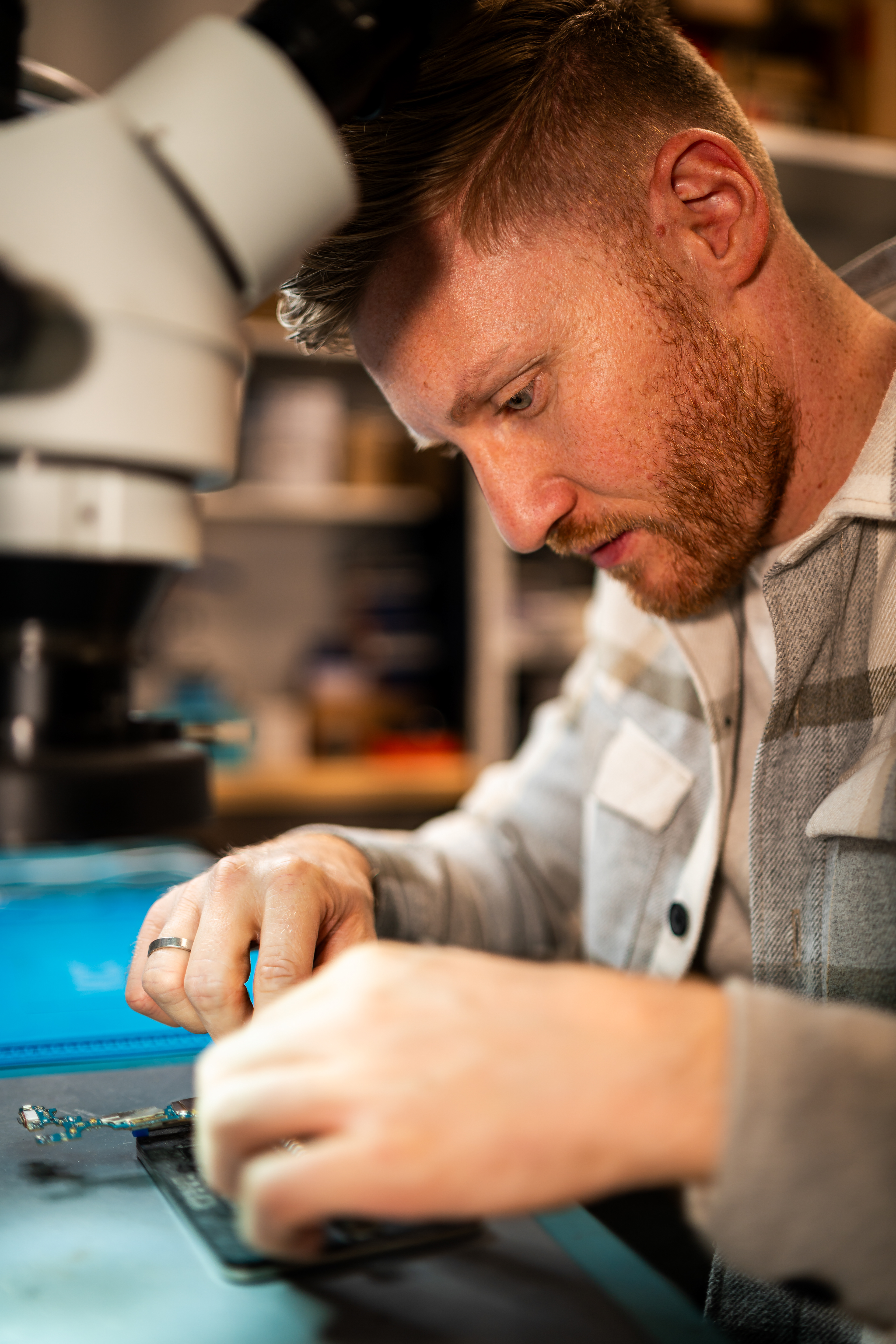 Professionelle Businessfotografie in Bad Waldsee: Techniker der Handyklinik bei der Vorbereitung einer Smartphone-Reparatur am hochmodernen Arbeitsplatz.