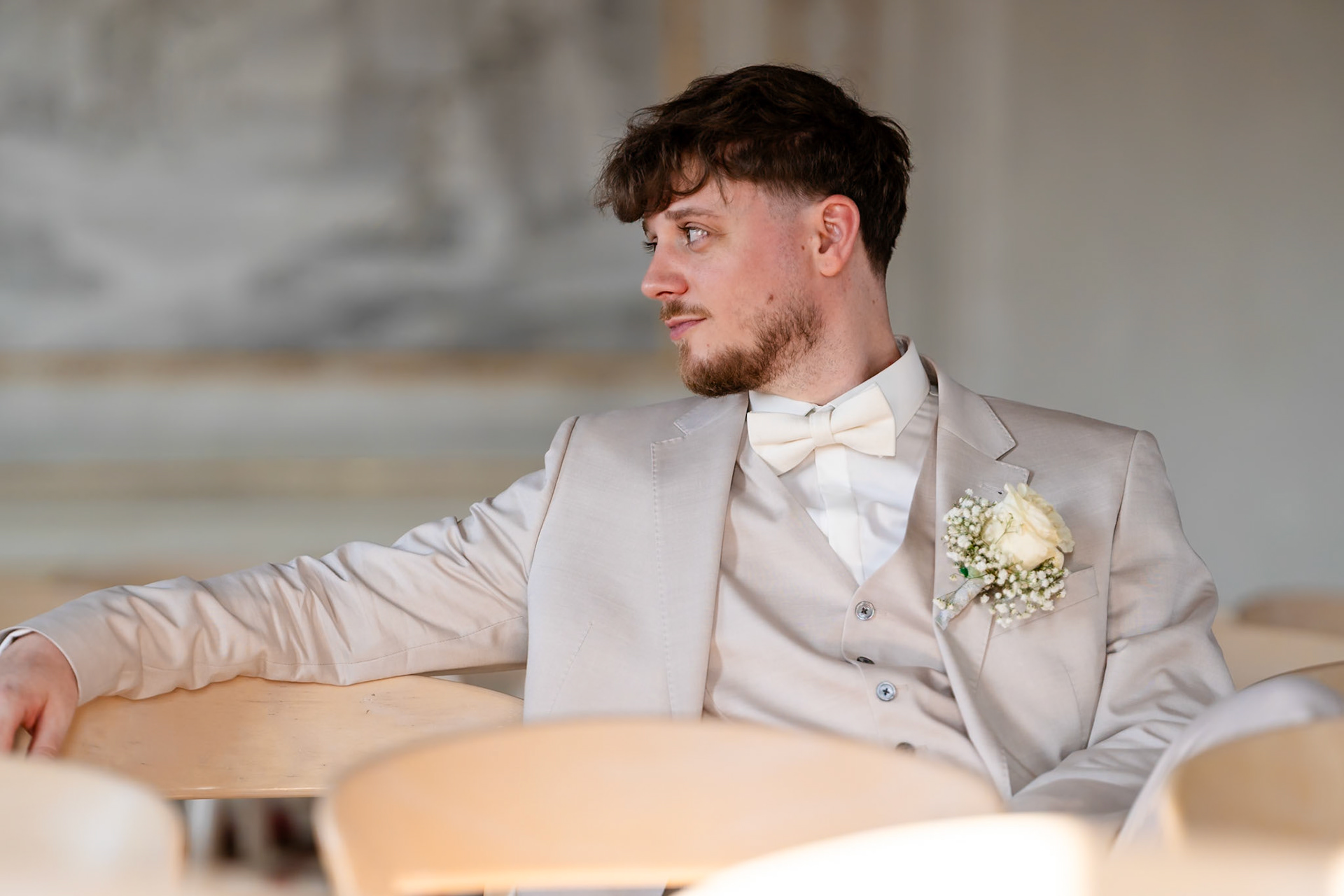 Bräutigam im hellen Hochzeitsanzug wartet entspannt auf seine Braut im Goldenen Saal Bad Buchau – MFuchsloch Hochzeitsfotografie & Videografie