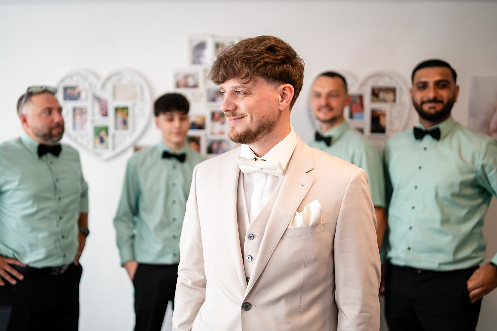 Bräutigam im hellen Hochzeitsanzug mit lächelnden Trauzeugen im Hintergrund – MFuchsloch Hochzeitsfotografie & Videografie