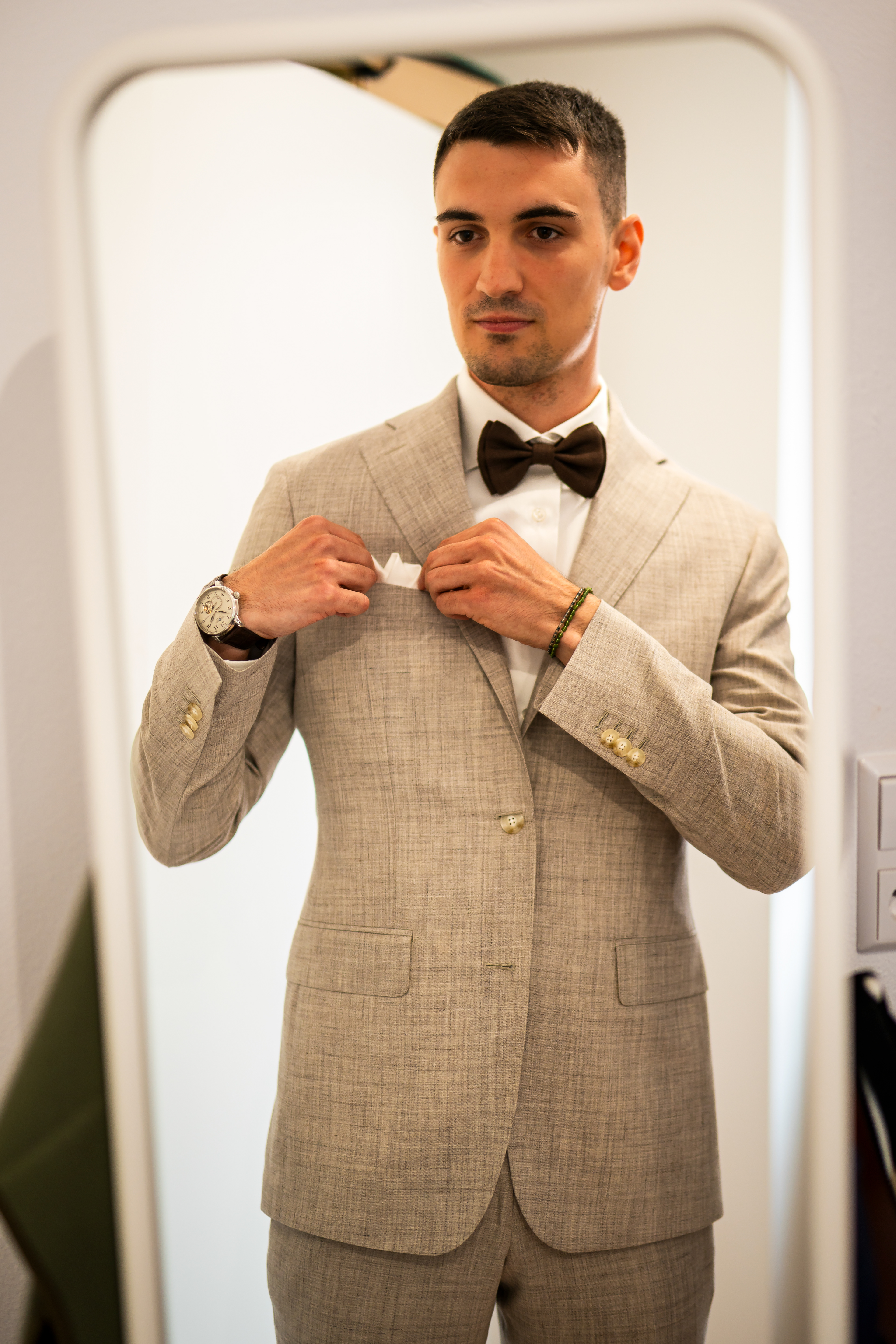 Bräutigam Simon richtet seine Fliege vor dem Spiegel. Porträtaufnahme während der Bräutigam-Vorbereitungen, fotografiert von MFUCHSLOCH Fotografie & Videografie.