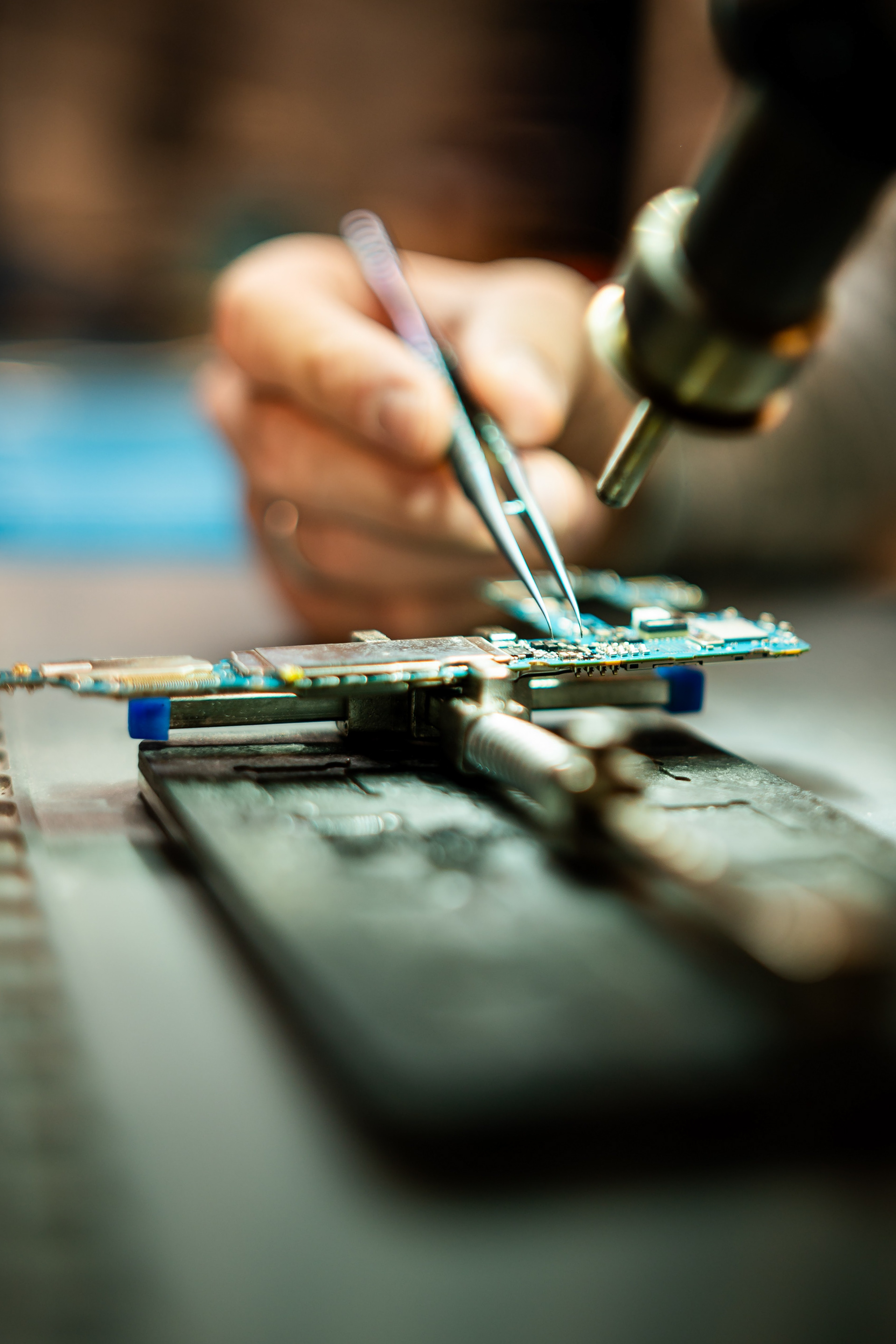 Makroaufnahme von Mikro-Lötarbeiten an einer Smartphone-Platine. Technische Industriefotografie für Fachbetriebe in Biberach und Bad Waldsee.