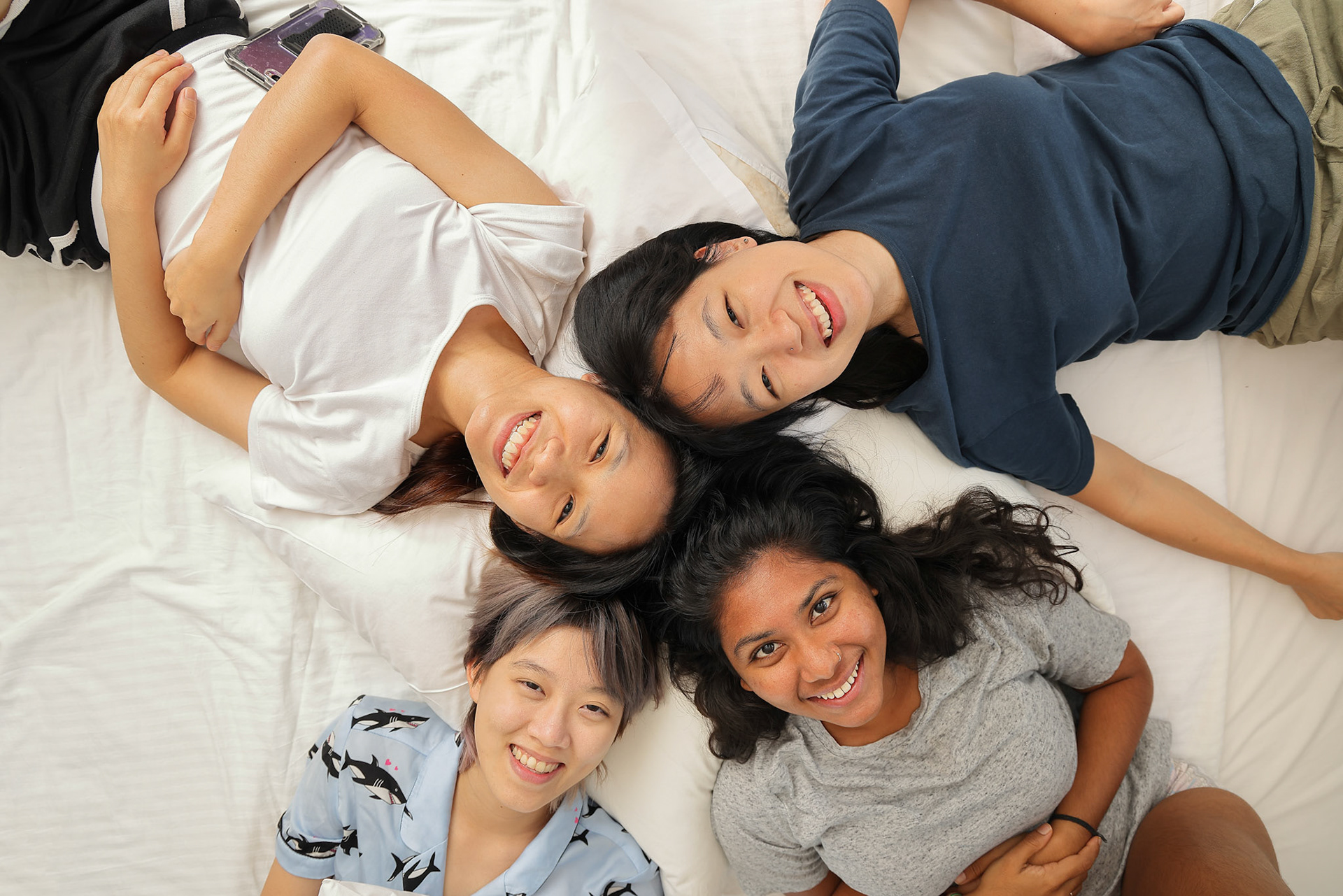 Young Asian girls sleepover pajama party happy joy funny laugh smile on large bed in bedroom with bright light window