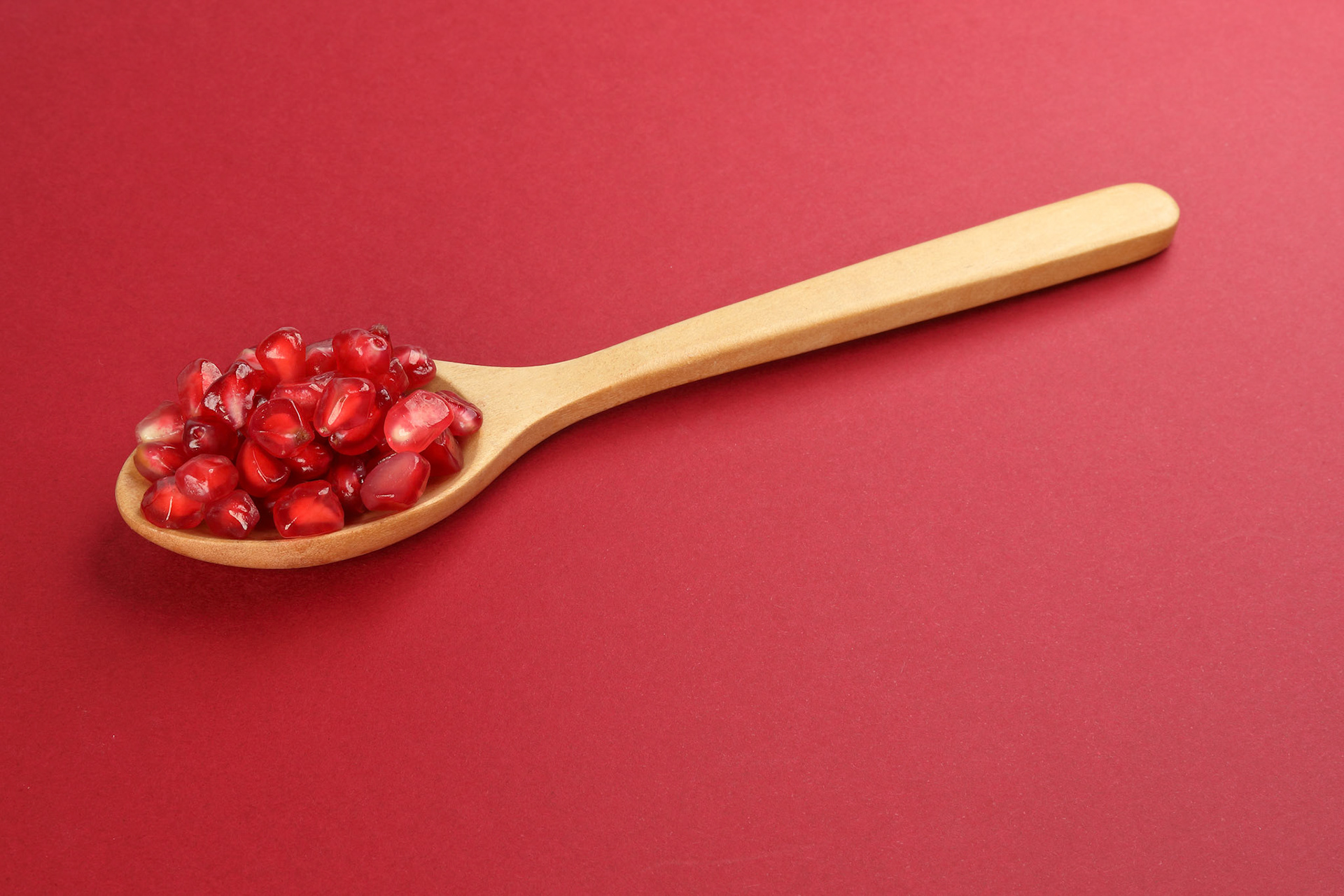 Red Pomegranate seed wooden spoon red paper background