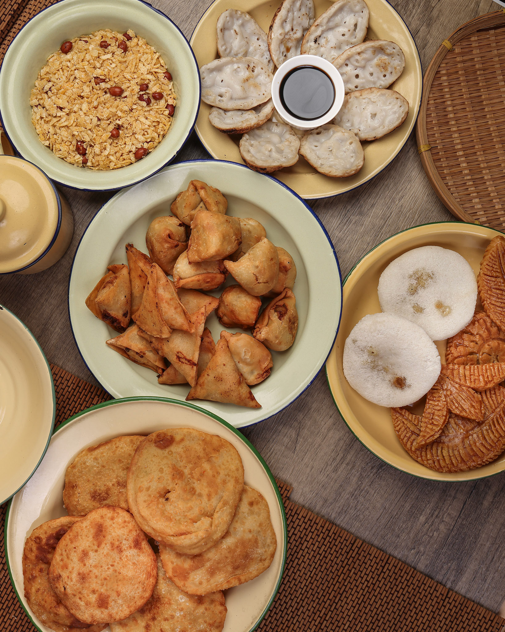 Bengali sweet savoury snacks variety stuffed pancake chitoi bhapa nakshi pakkon pitha singara samosa dal aloo puri fried flattened rice cheera mix on enamel tin metal plate over rustic background