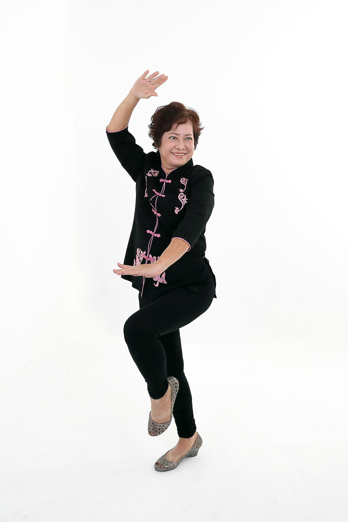 Elderly asian Chinese female wearing black tang samfu on white background exercise tai chi