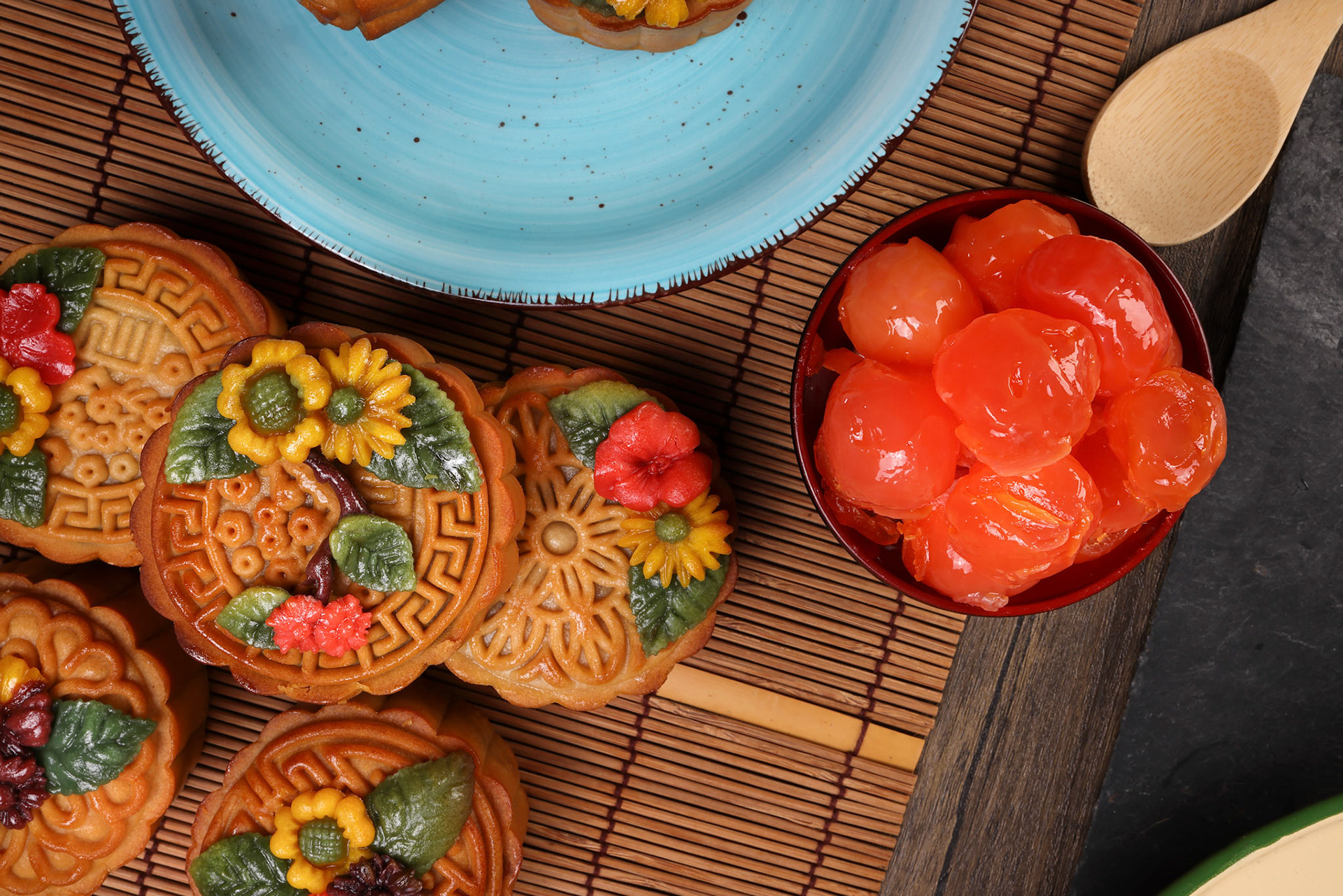 Mid autumn festive colorful flower decorated moon cake making ingredients salted egg yolk cut slice on blue ceramic plate background on bamboo food mat